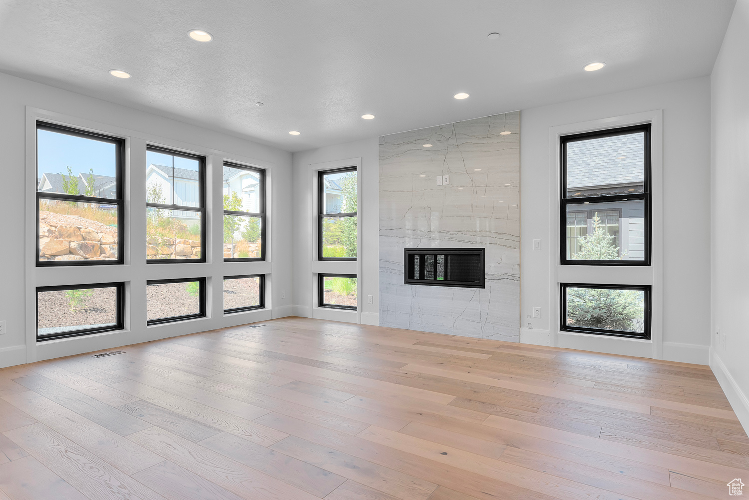 Unfurnished living room with light wood-type flooring, a tile fireplace, and tile walls