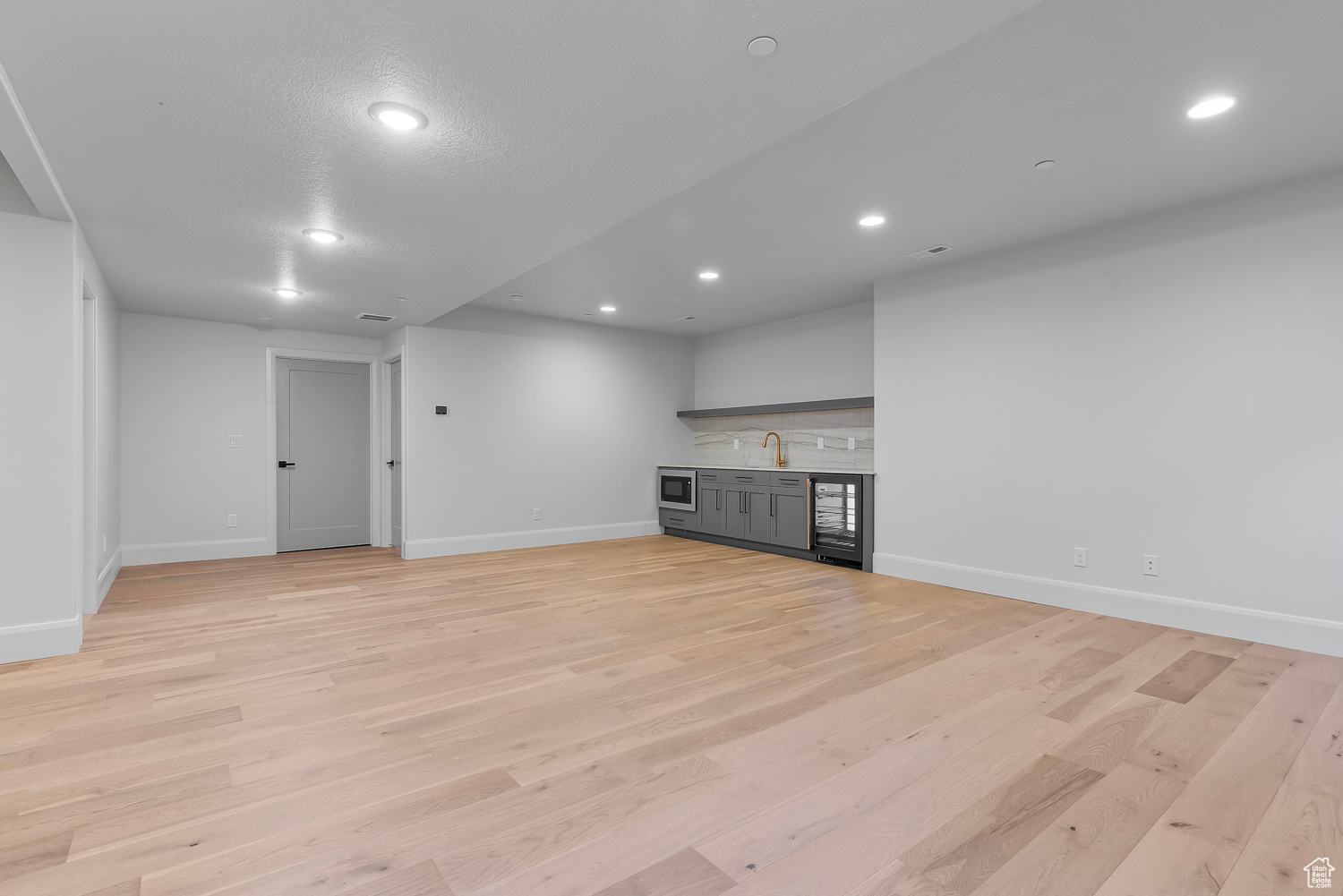 Unfurnished living room featuring sink and light hardwood / wood-style flooring