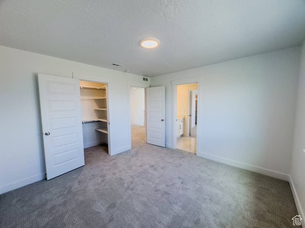 Unfurnished bedroom featuring carpet, a closet, and a spacious closet