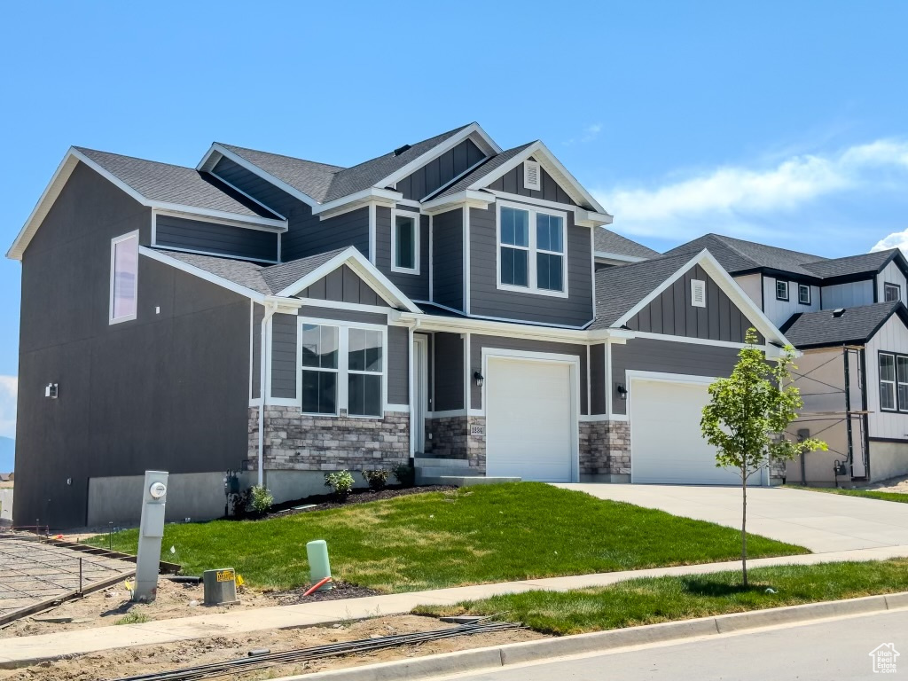 Craftsman-style home featuring a garage and a front lawn