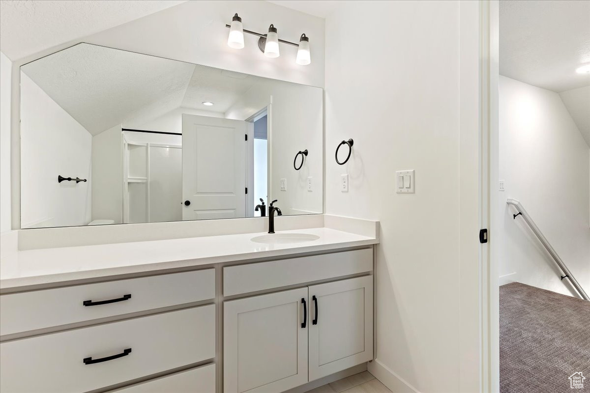 Bathroom featuring lofted ceiling and vanity