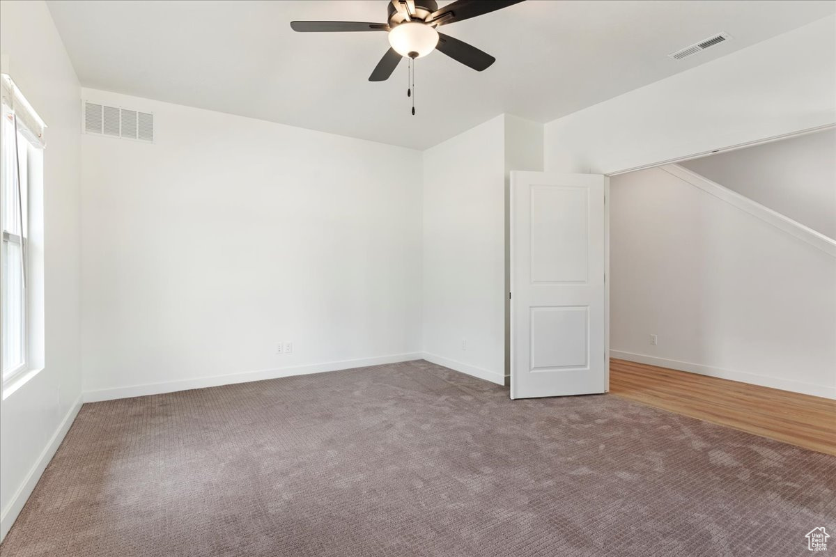 Carpeted spare room featuring ceiling fan