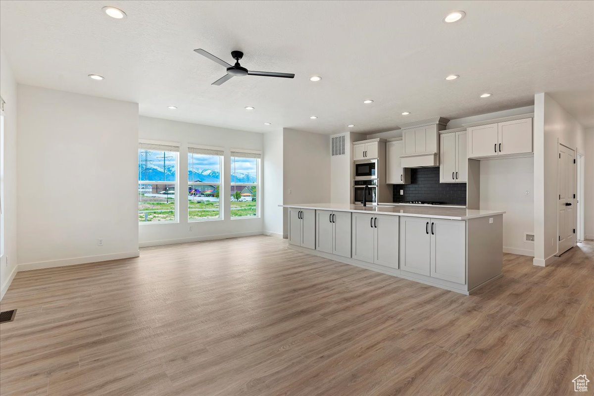 Kitchen with a center island with sink and light wood-type flooring