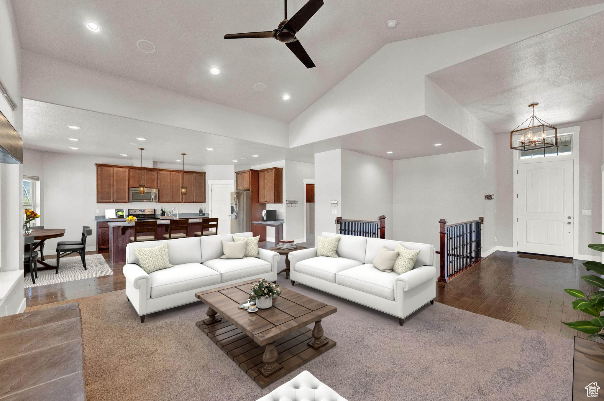 Living room featuring high vaulted ceiling, ceiling fan with notable chandelier, and dark wood-type flooring