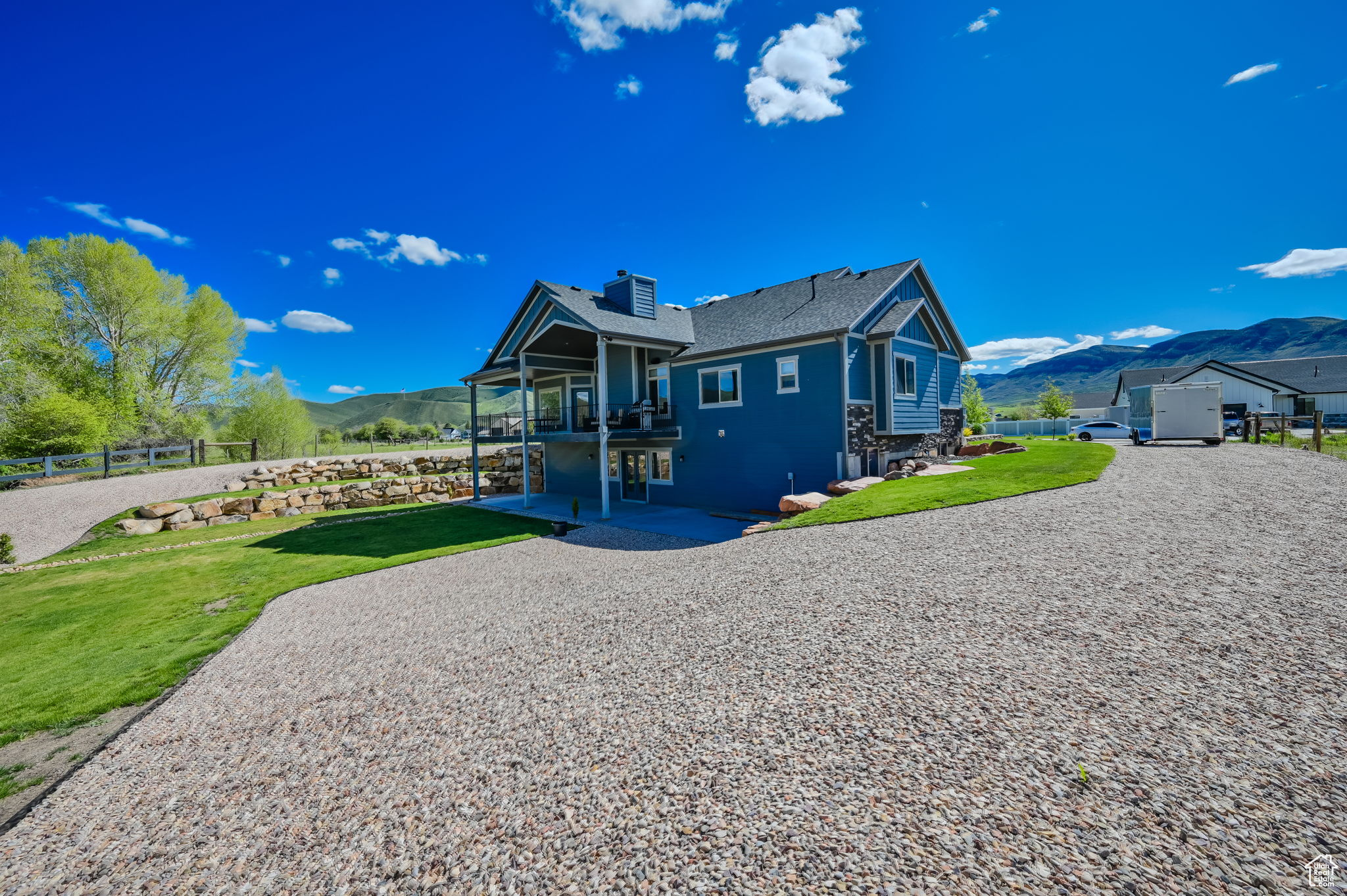 Rear view of property with a patio area, an outdoor structure, a mountain view, and a yard