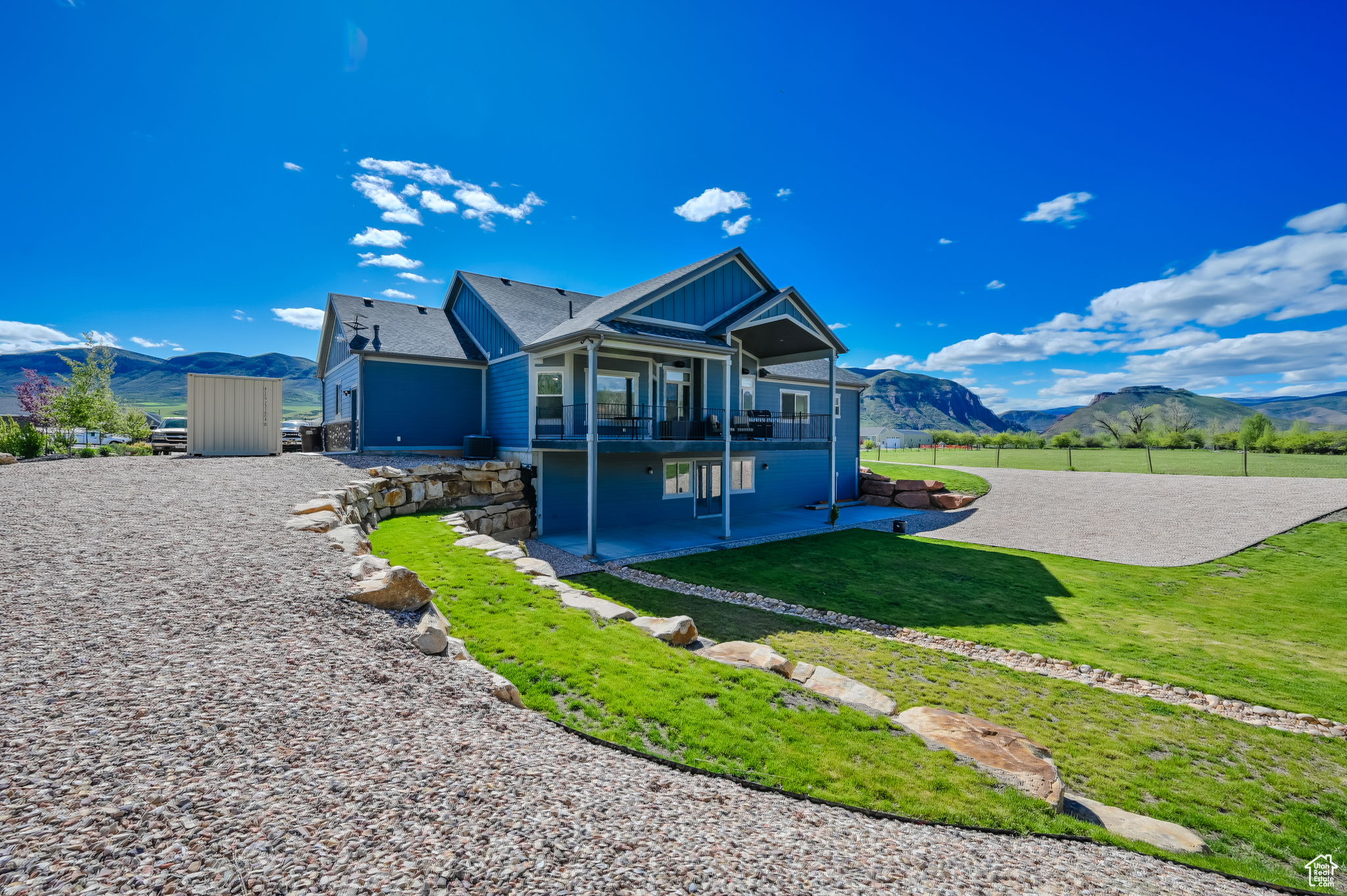 View of front of property featuring a patio area, a shed, a front yard, and a mountain view