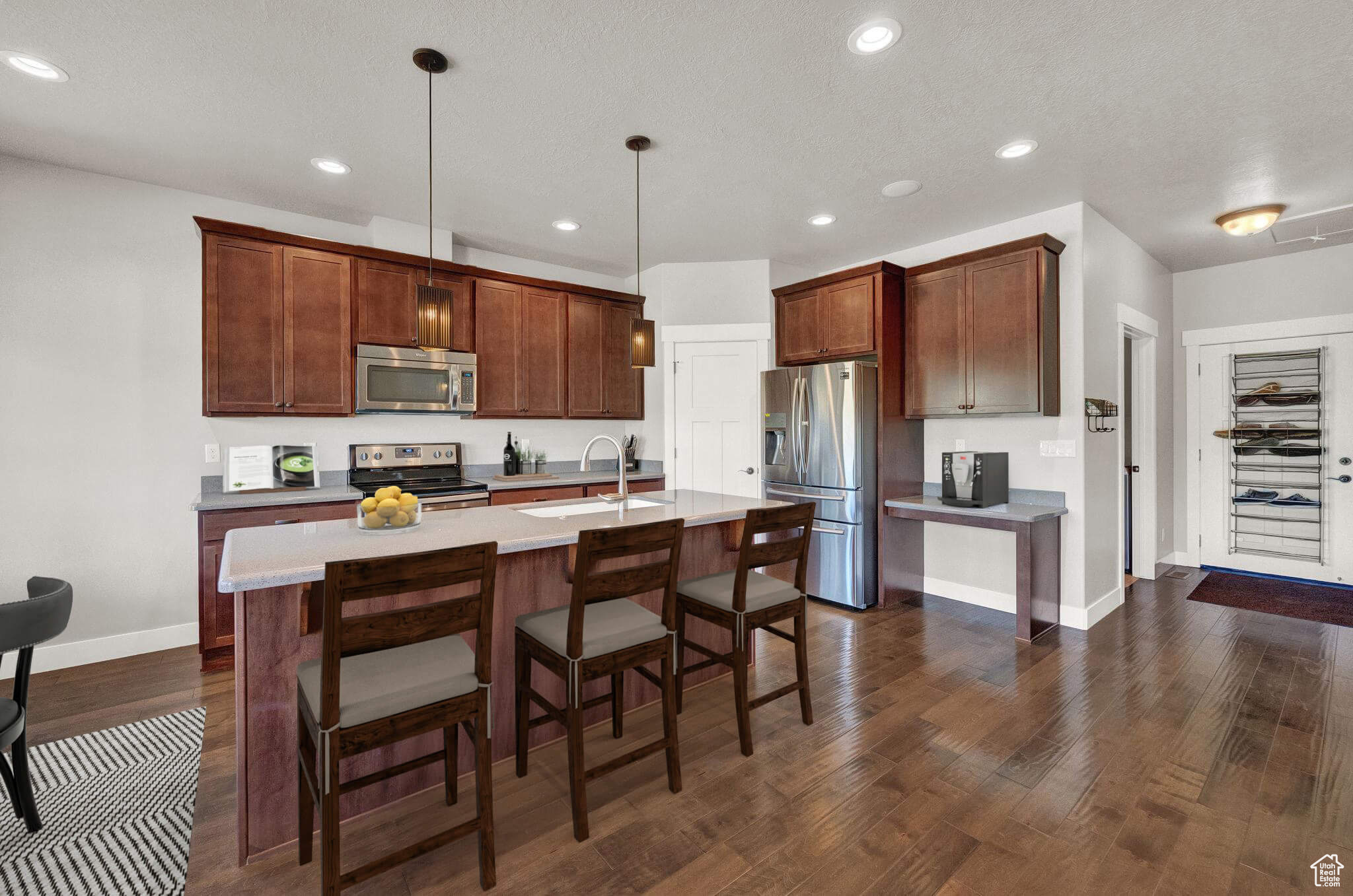 Kitchen with pendant lighting, dark hardwood / wood-style flooring, sink, a kitchen island with sink, and appliances with stainless steel finishes