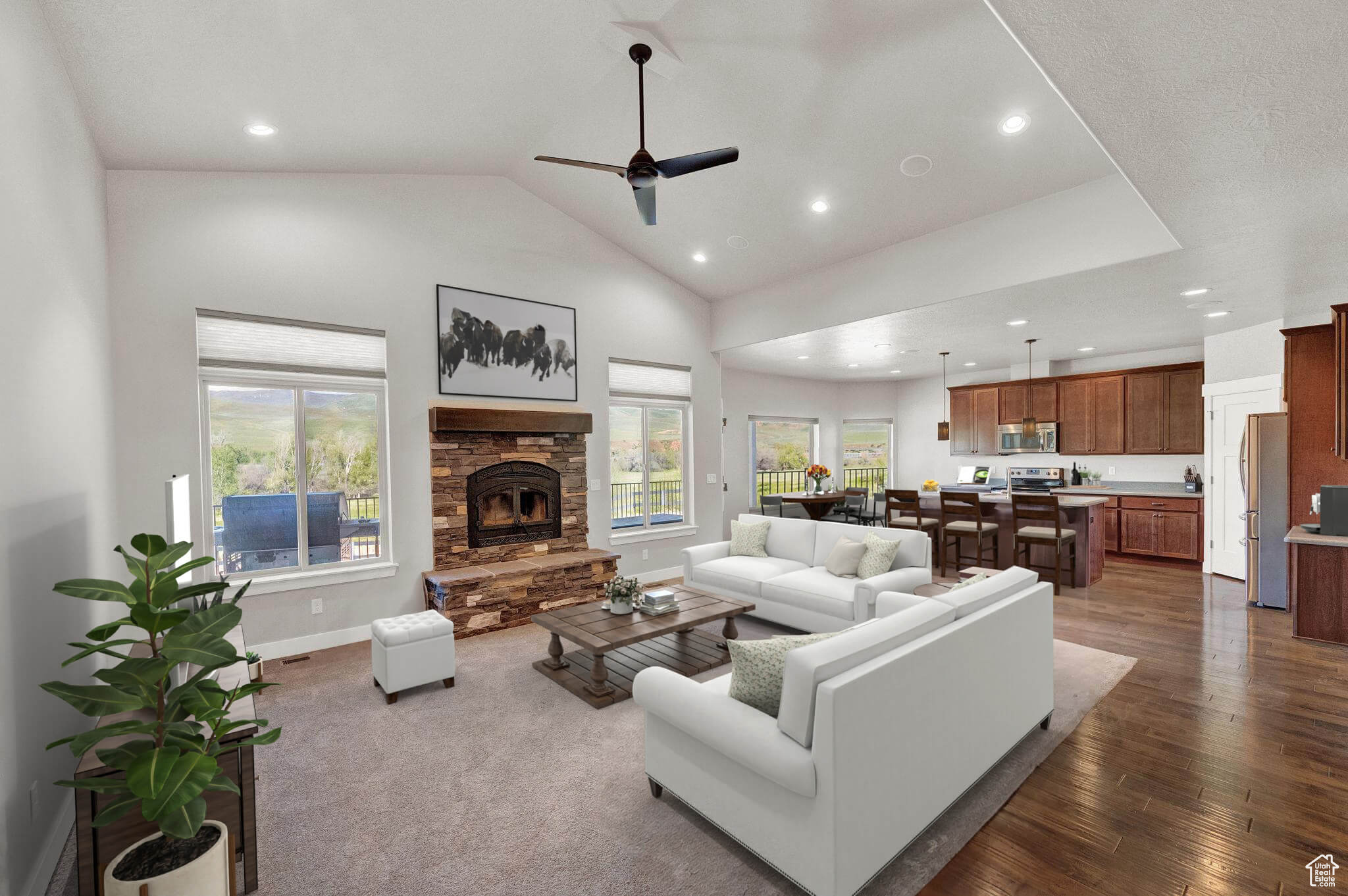 Living room with high vaulted ceiling, ceiling fan, a stone fireplace, and dark colored carpet