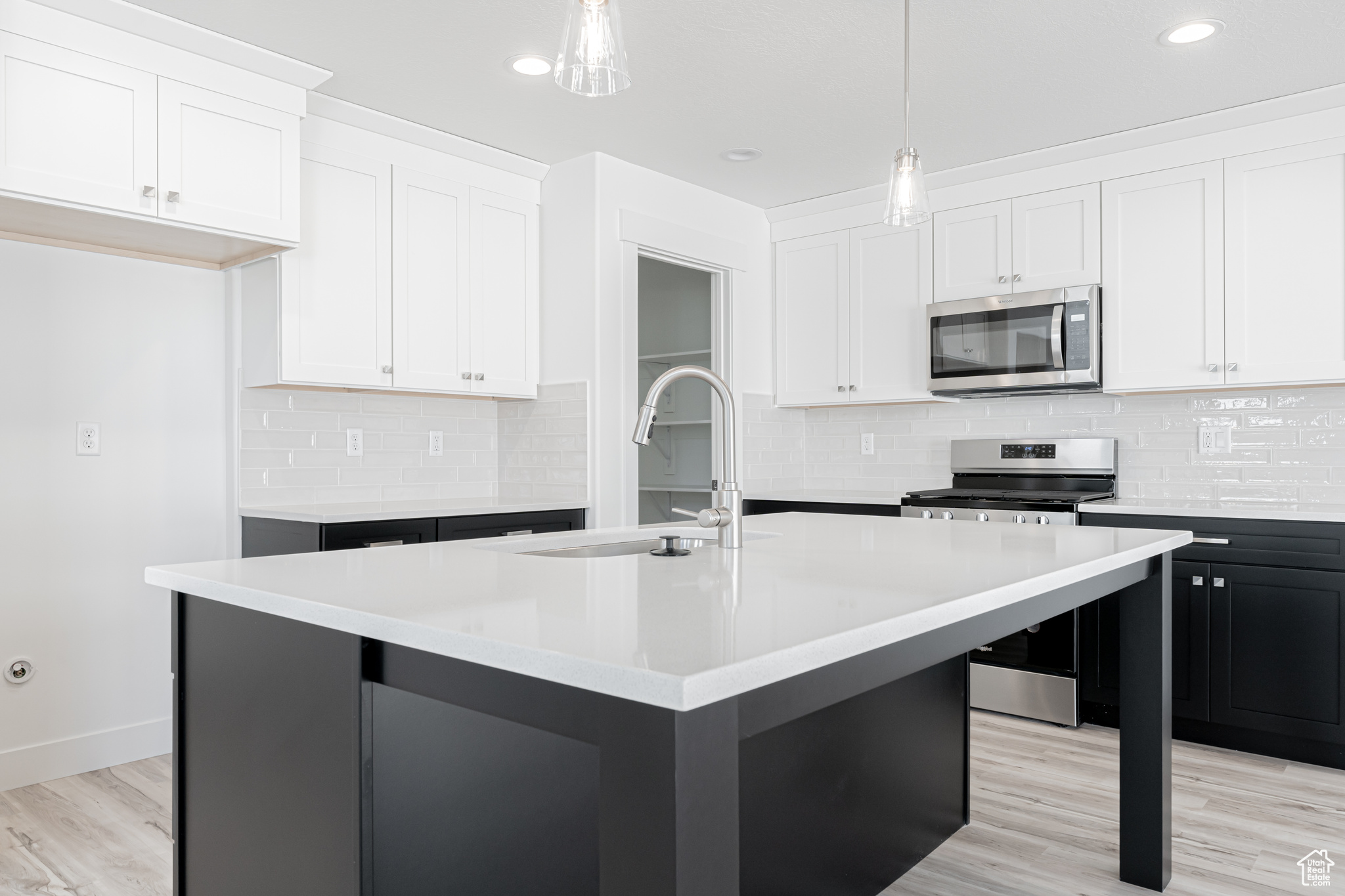 Kitchen with an island with sink, white cabinetry, and stainless steel appliances