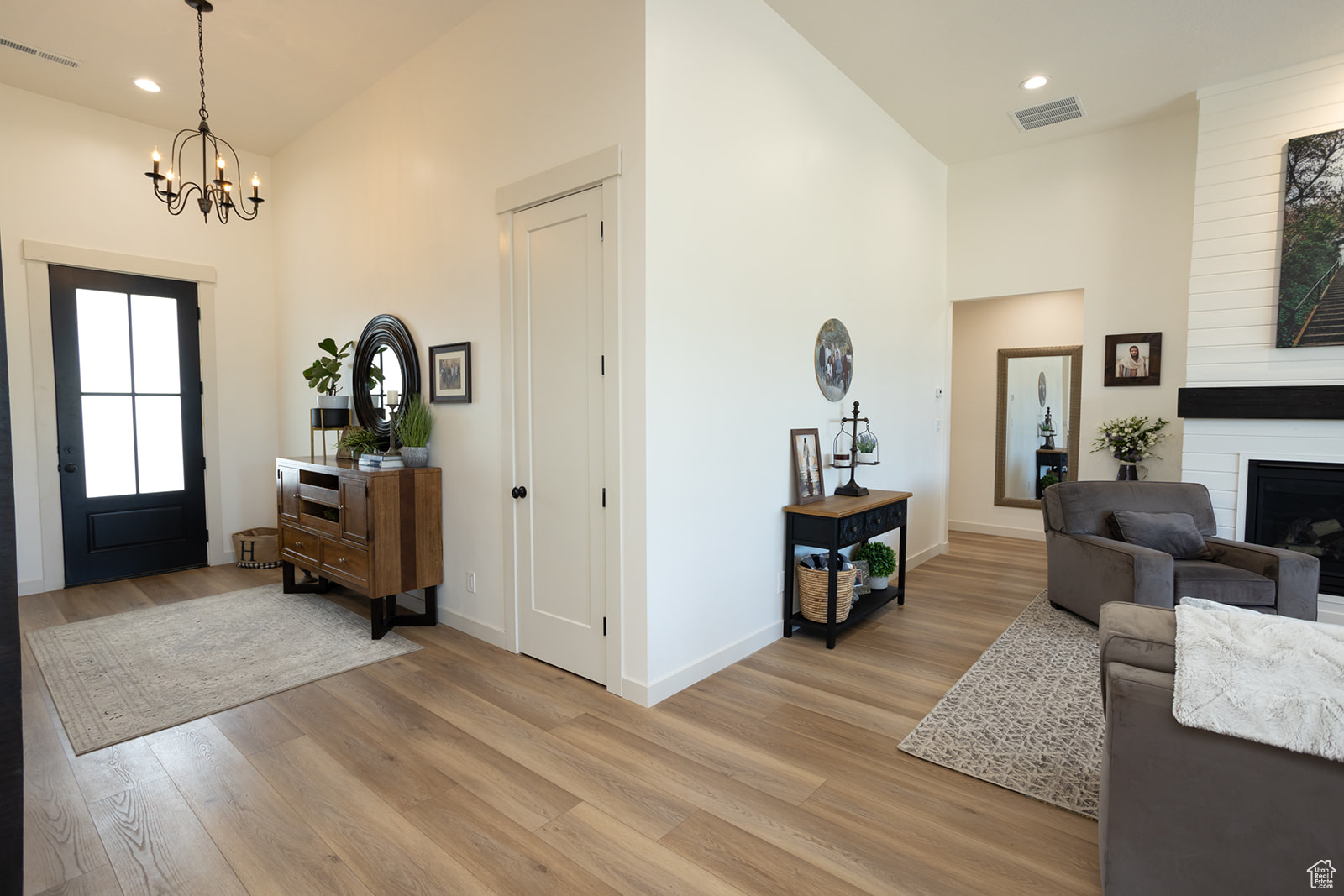 Entryway with an inviting chandelier, a towering ceiling, light hardwood / wood-style flooring, and a fireplace