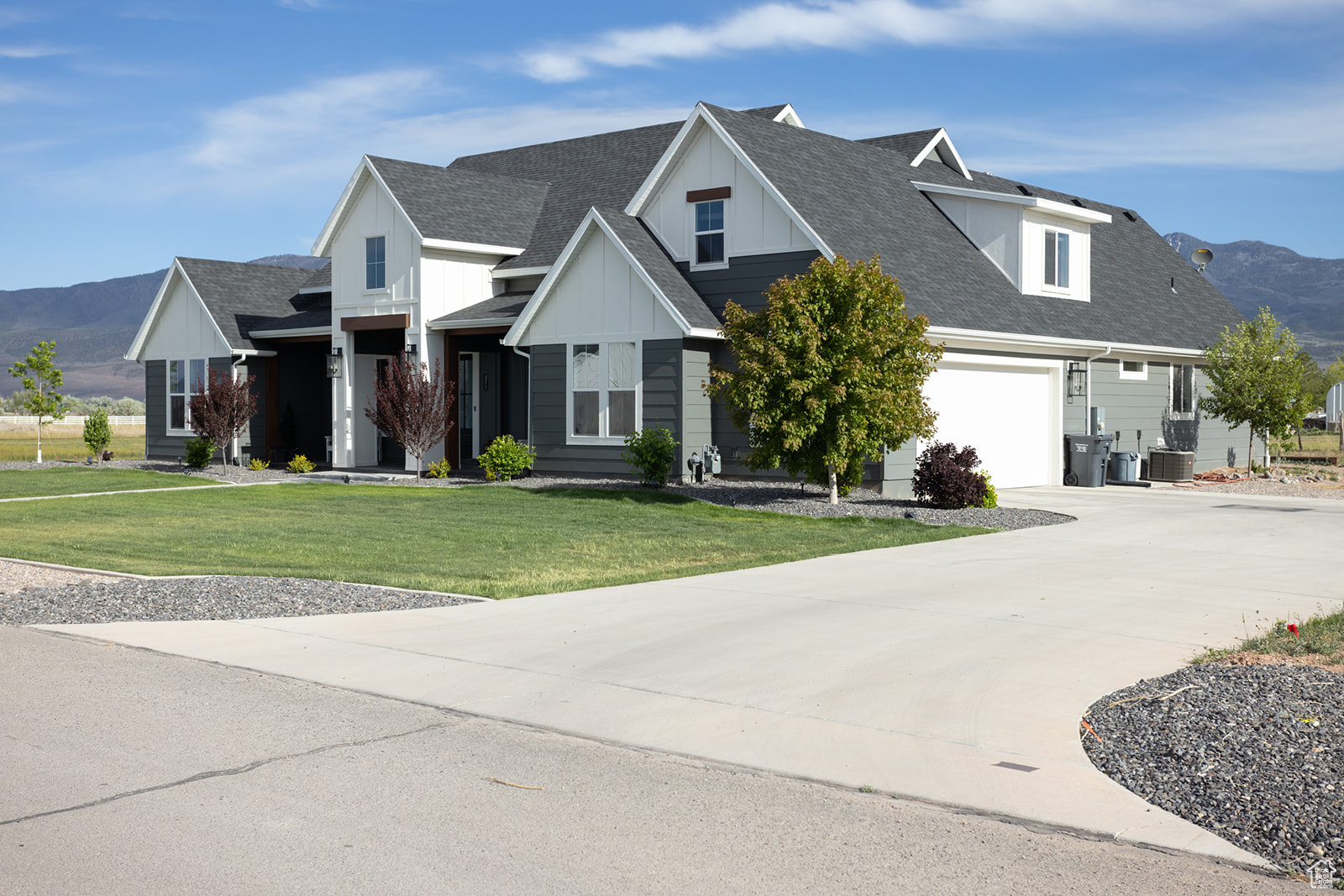 View of front of property with a garage, a mountain view, a front yard, and central air condition unit