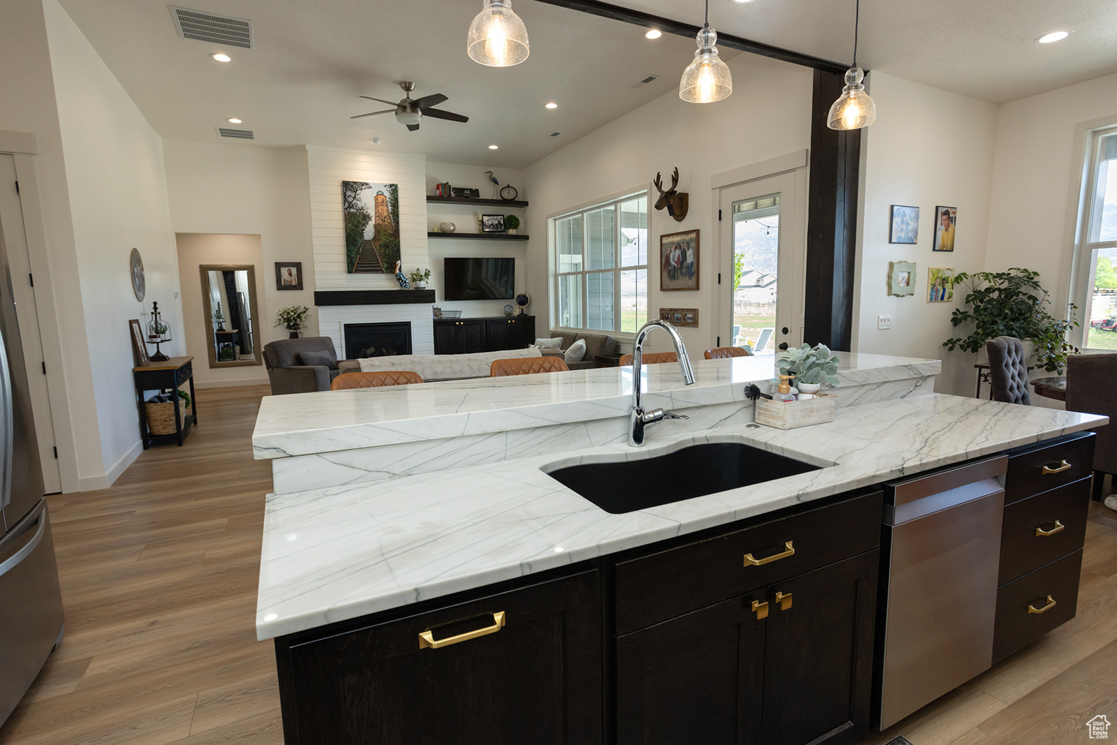 Kitchen with light hardwood / wood-style flooring, dishwasher, a center island with sink, sink, and pendant lighting