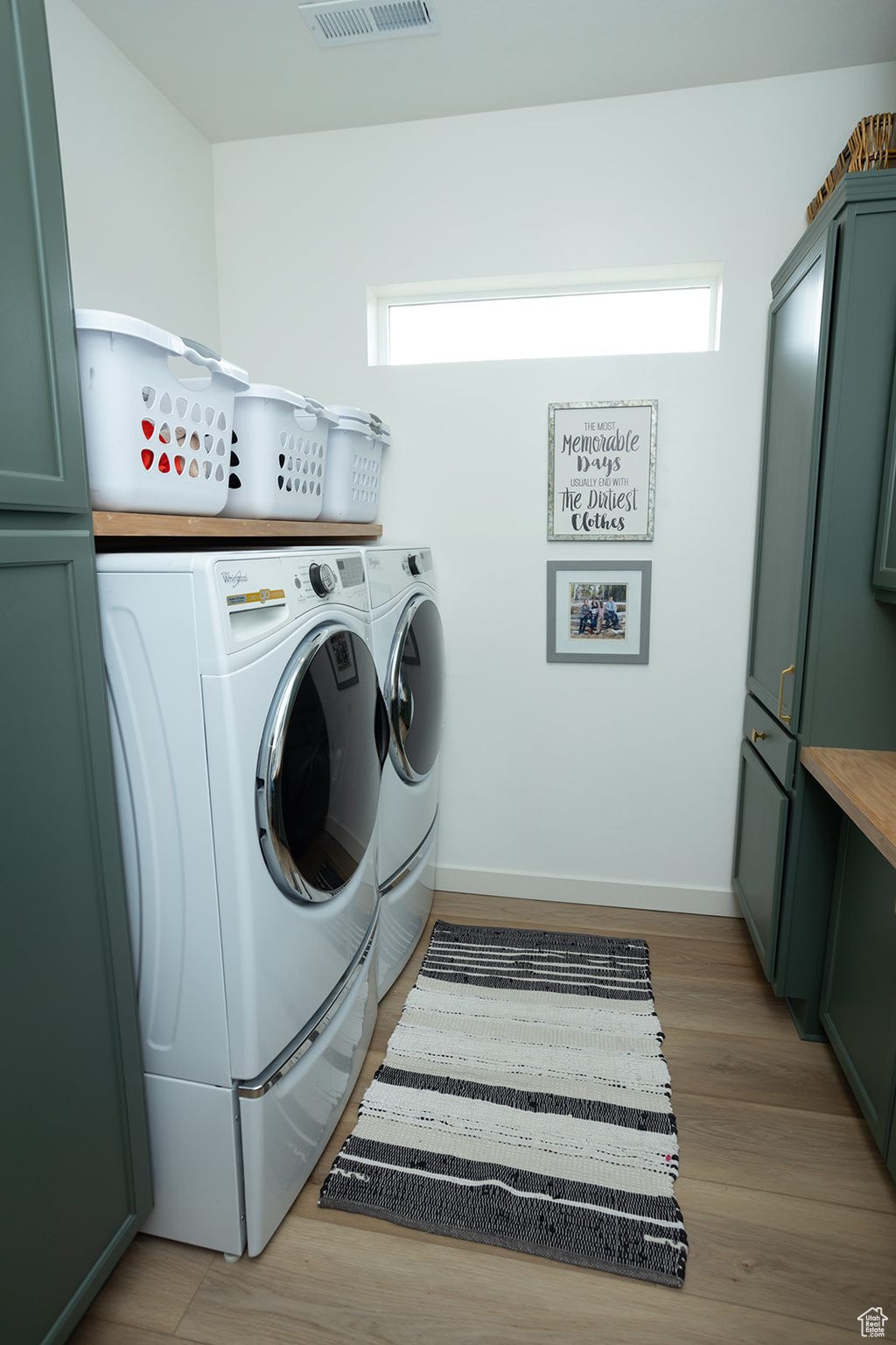 Laundry room with light hardwood / wood-style floors, plenty of natural light, and washing machine and clothes dryer