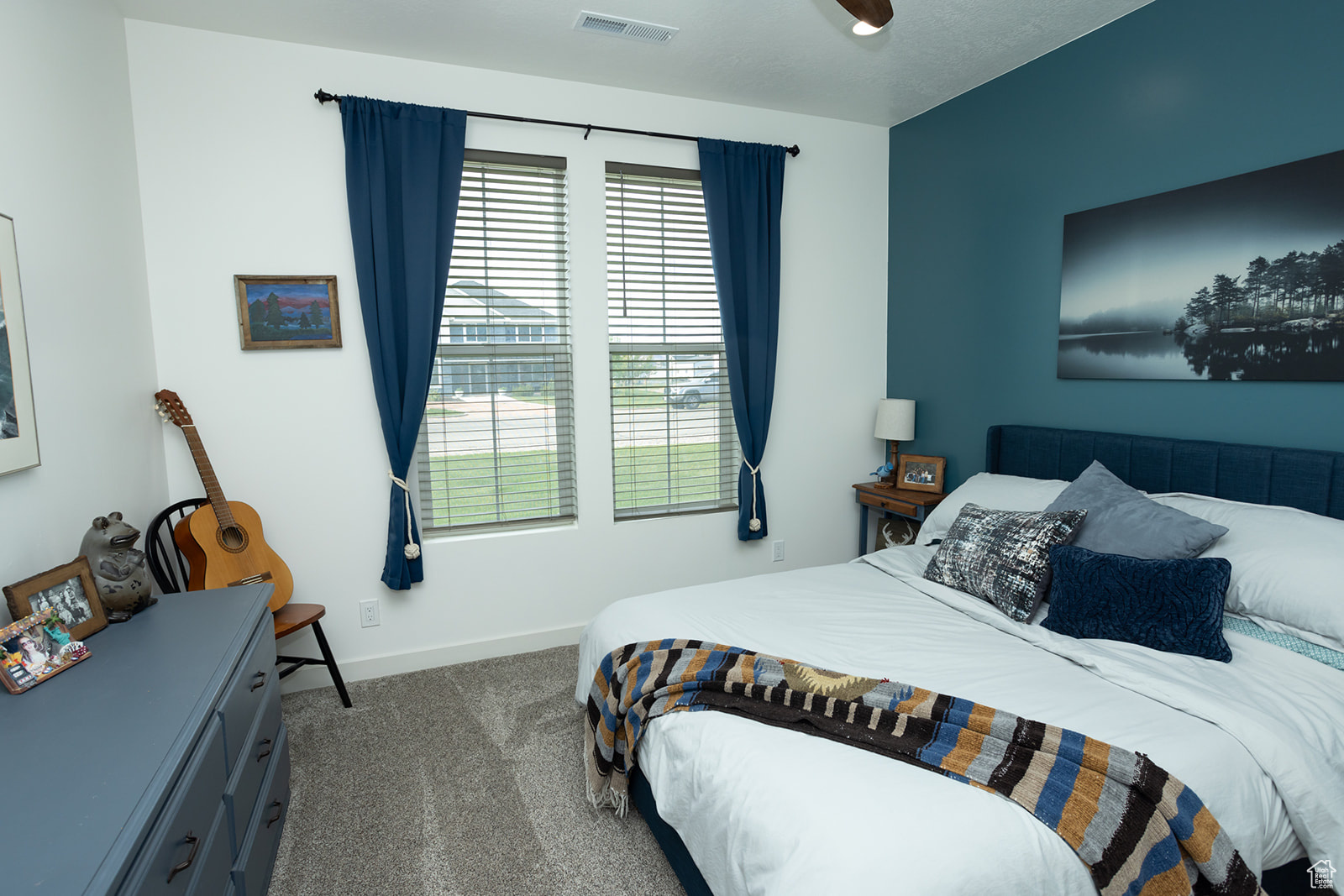 Carpeted bedroom featuring ceiling fan and multiple windows