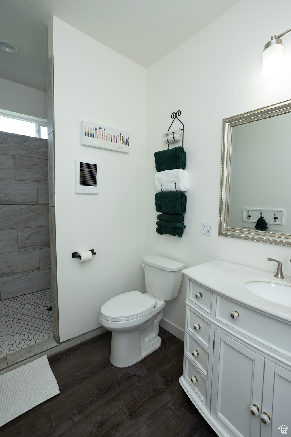 Bathroom featuring a tile shower, hardwood / wood-style flooring, toilet, and vanity