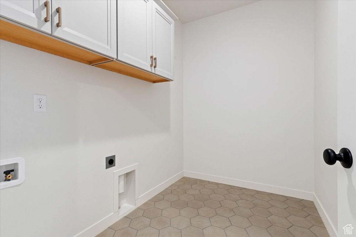 Laundry room with electric dryer hookup, cabinets, light tile patterned floors, and washer hookup