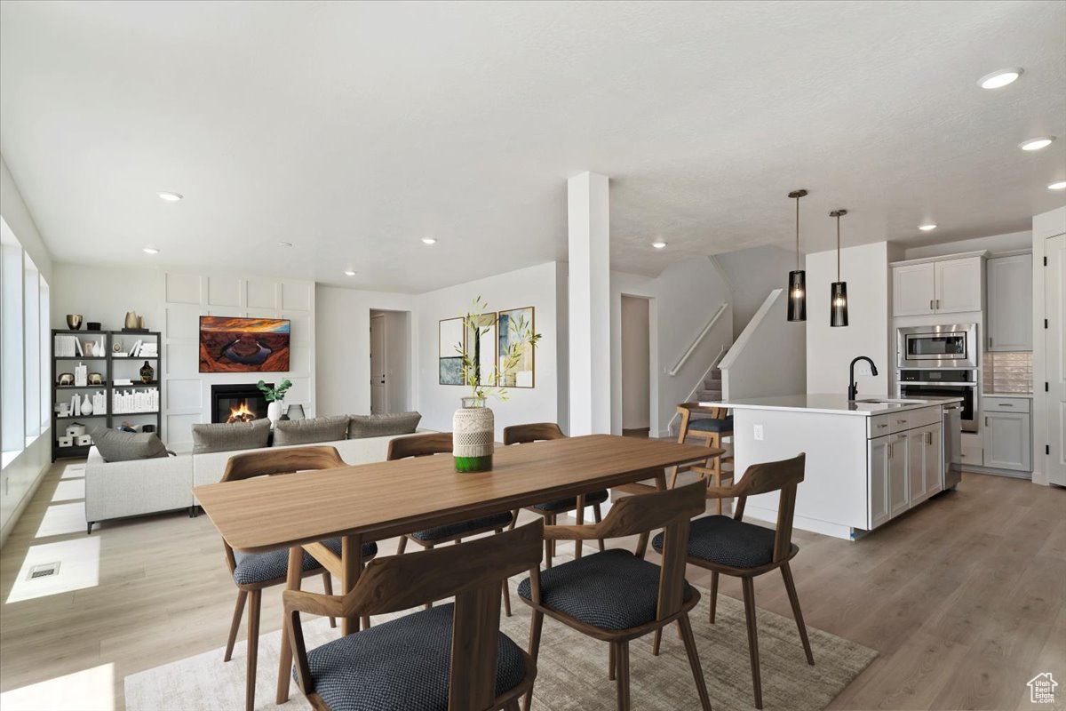 Dining space featuring light hardwood / wood-style floors, sink, and a large fireplace