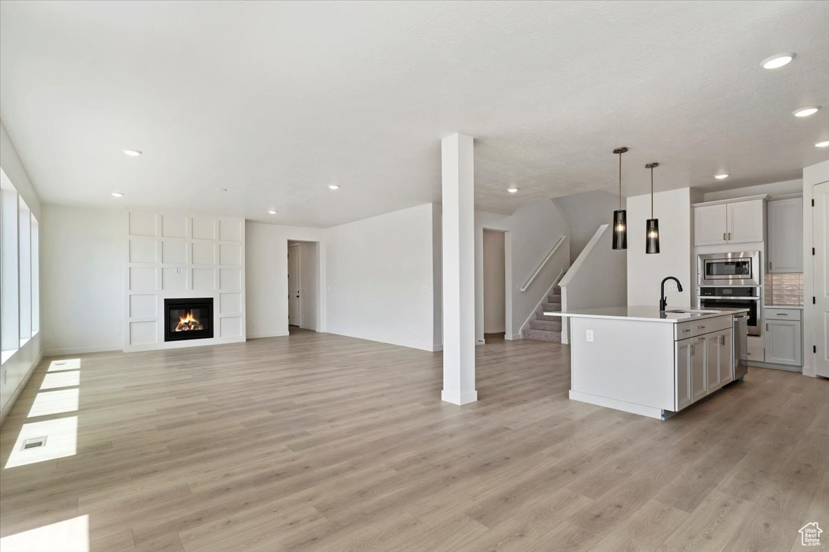 Unfurnished living room featuring sink, light hardwood / wood-style flooring, and a fireplace