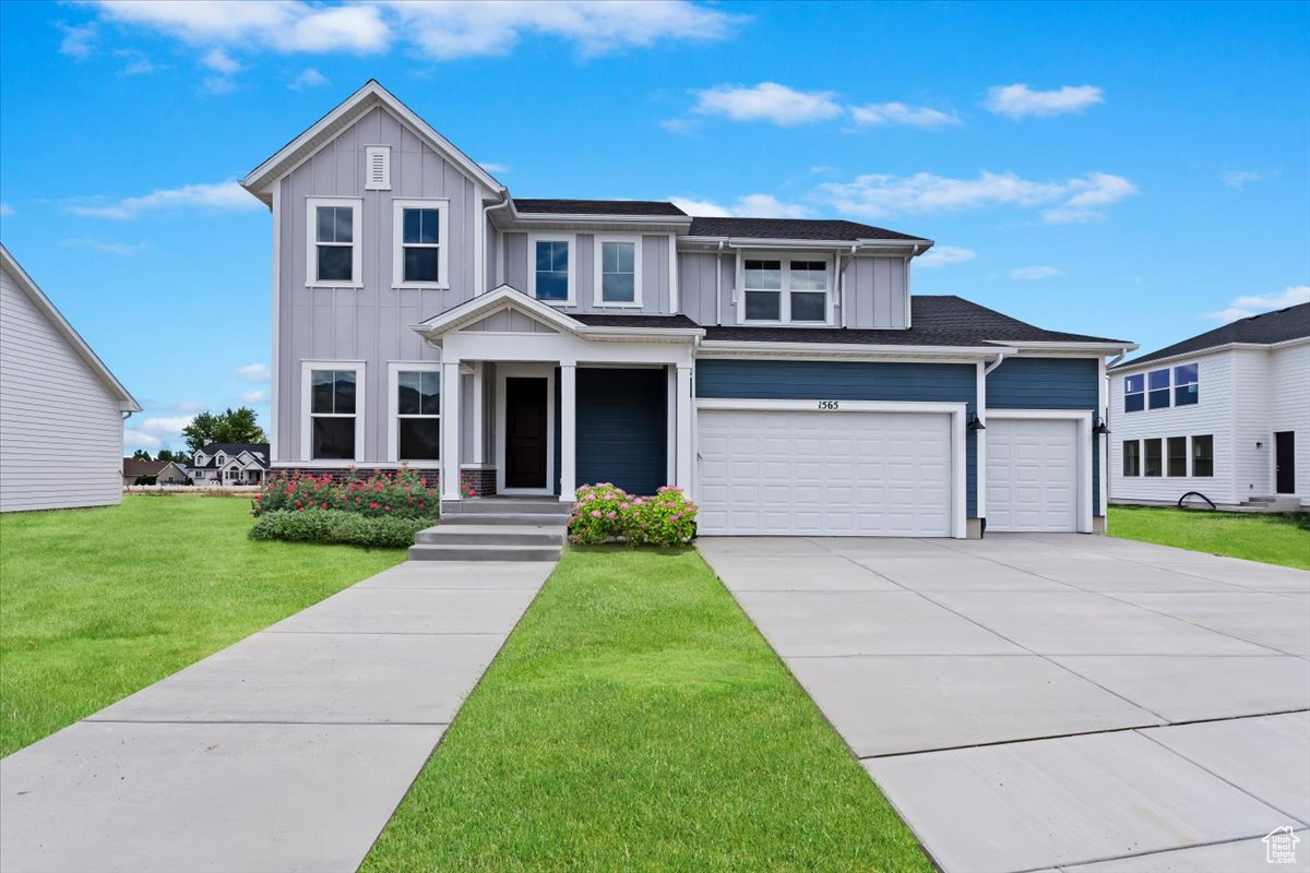 View of front facade featuring a garage and a front lawn