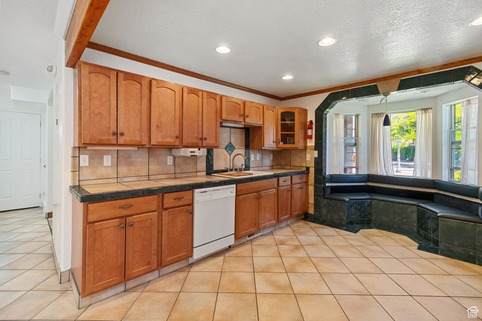 Kitchen with sink, dishwasher, backsplash, and light tile floors