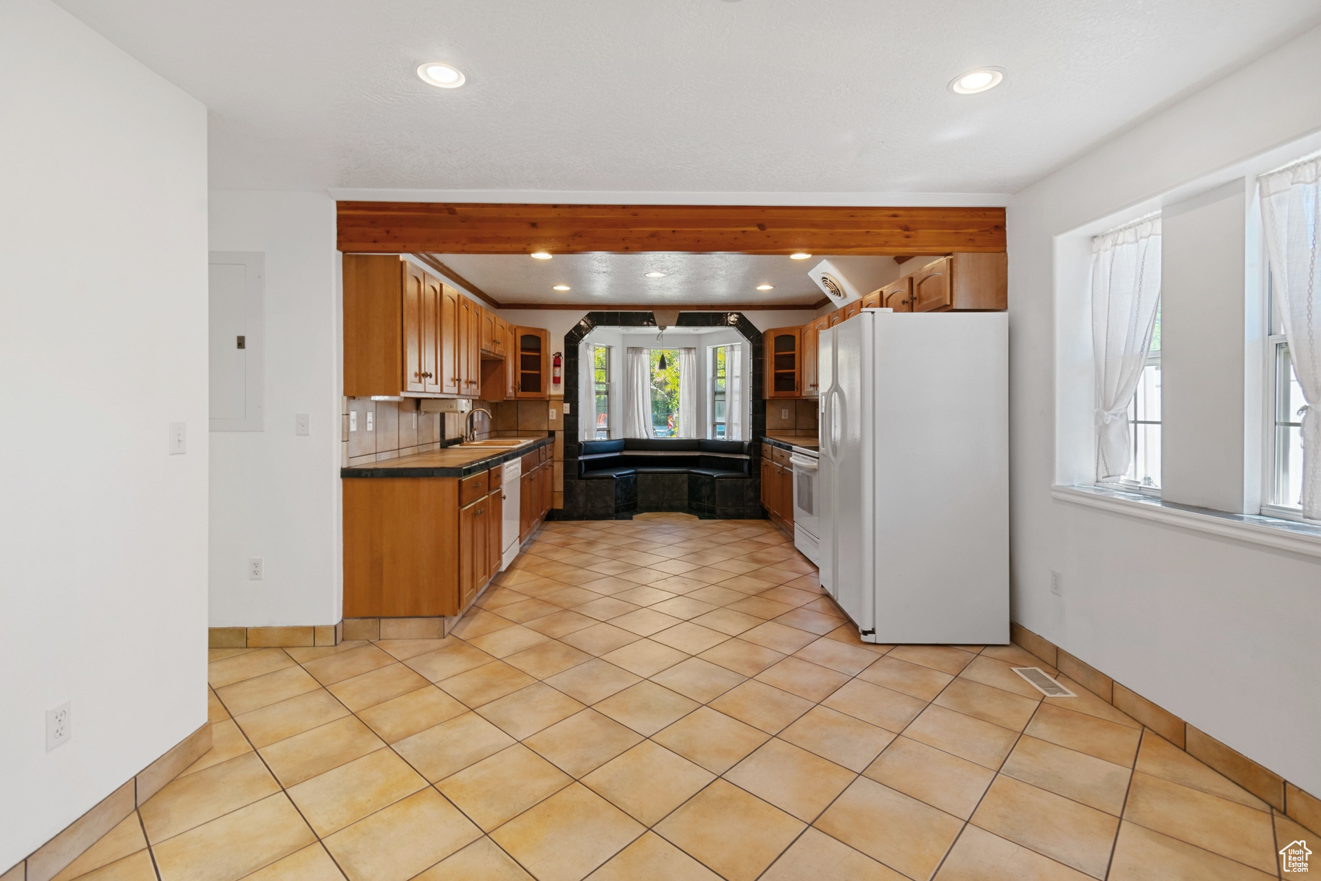 Kitchen with sink, light tile floors, white appliances, and backsplash