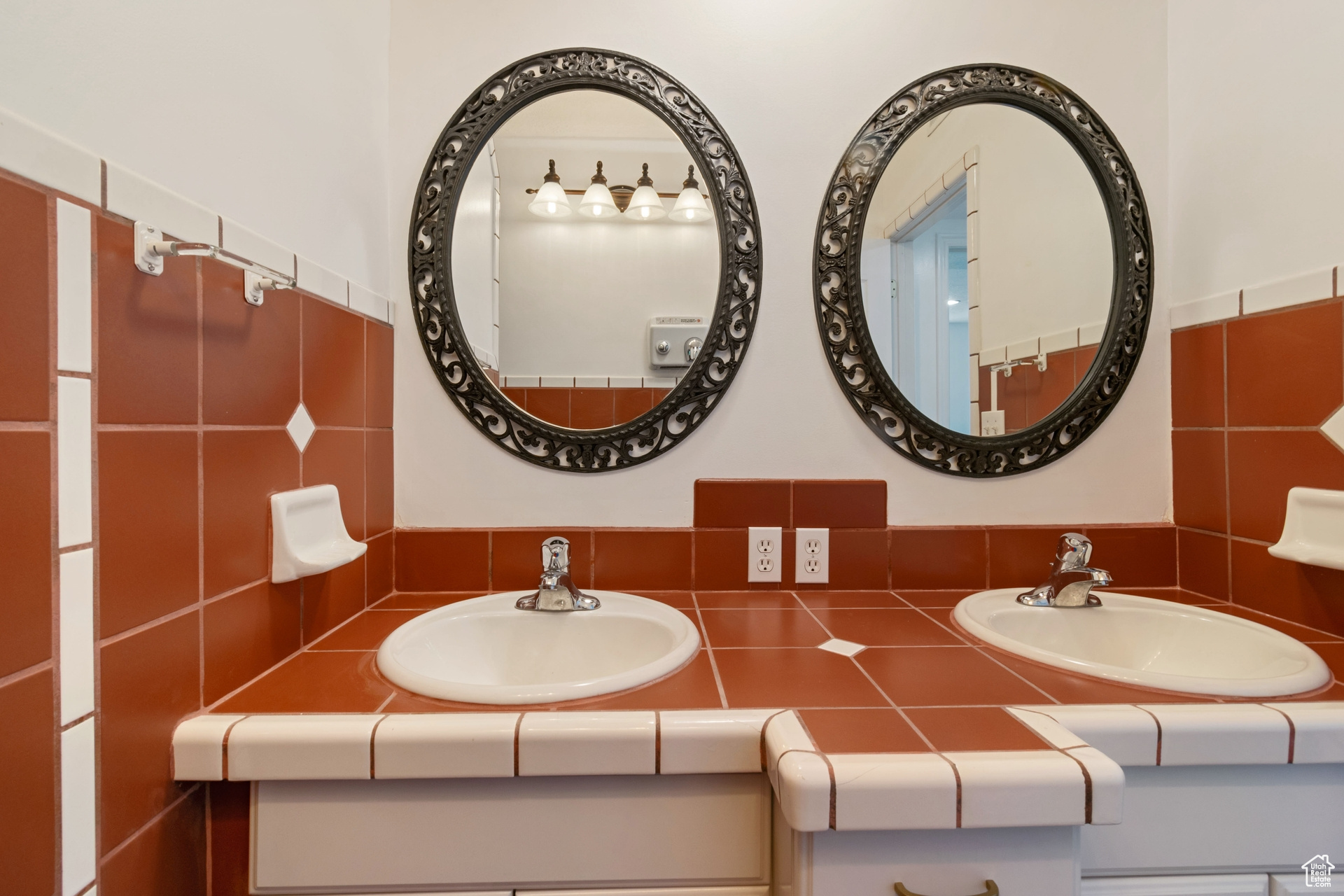 Bathroom with double sink, vanity with extensive cabinet space, and tile walls