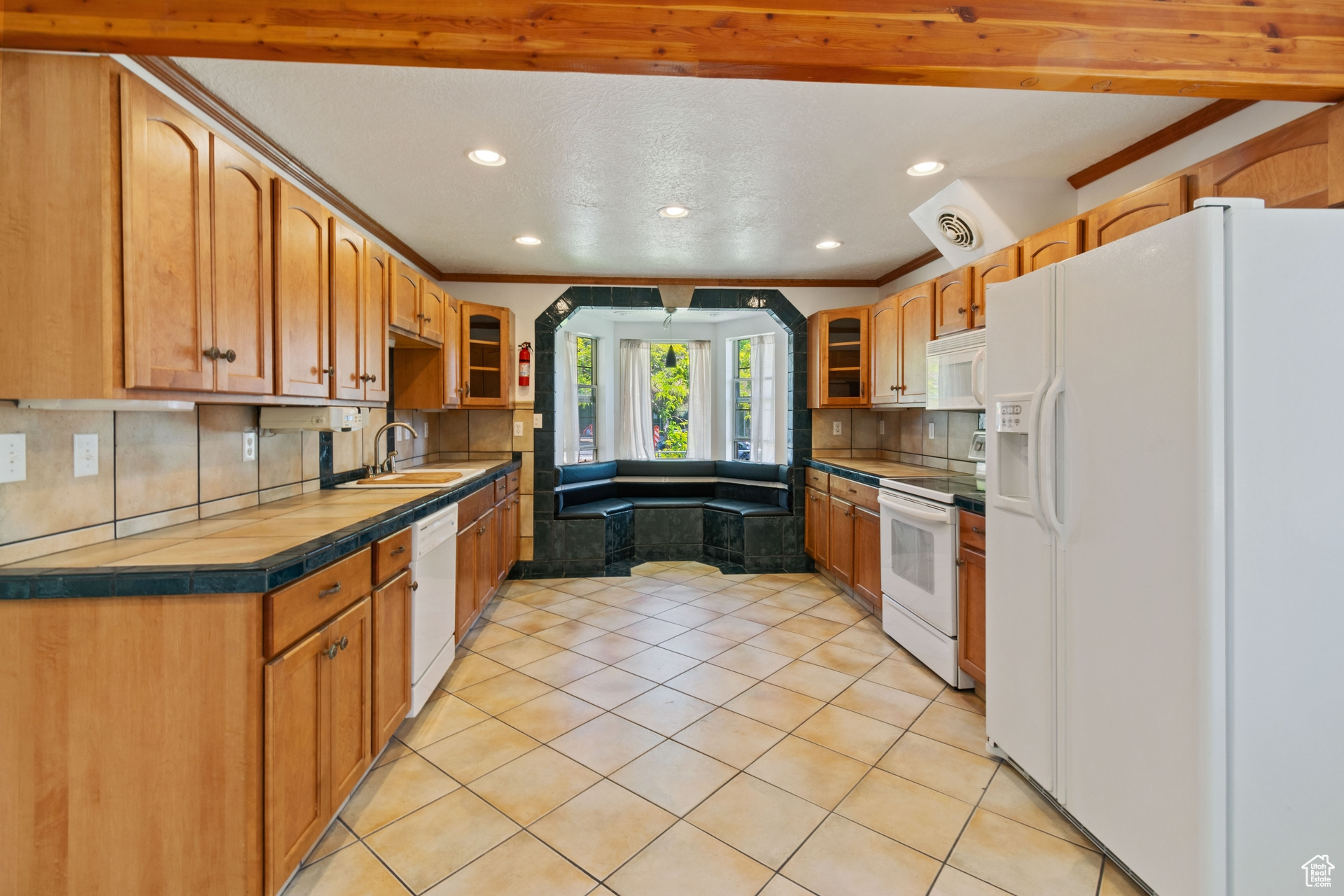 Kitchen featuring crown molding, white appliances, backsplash, sink, and light tile flooring