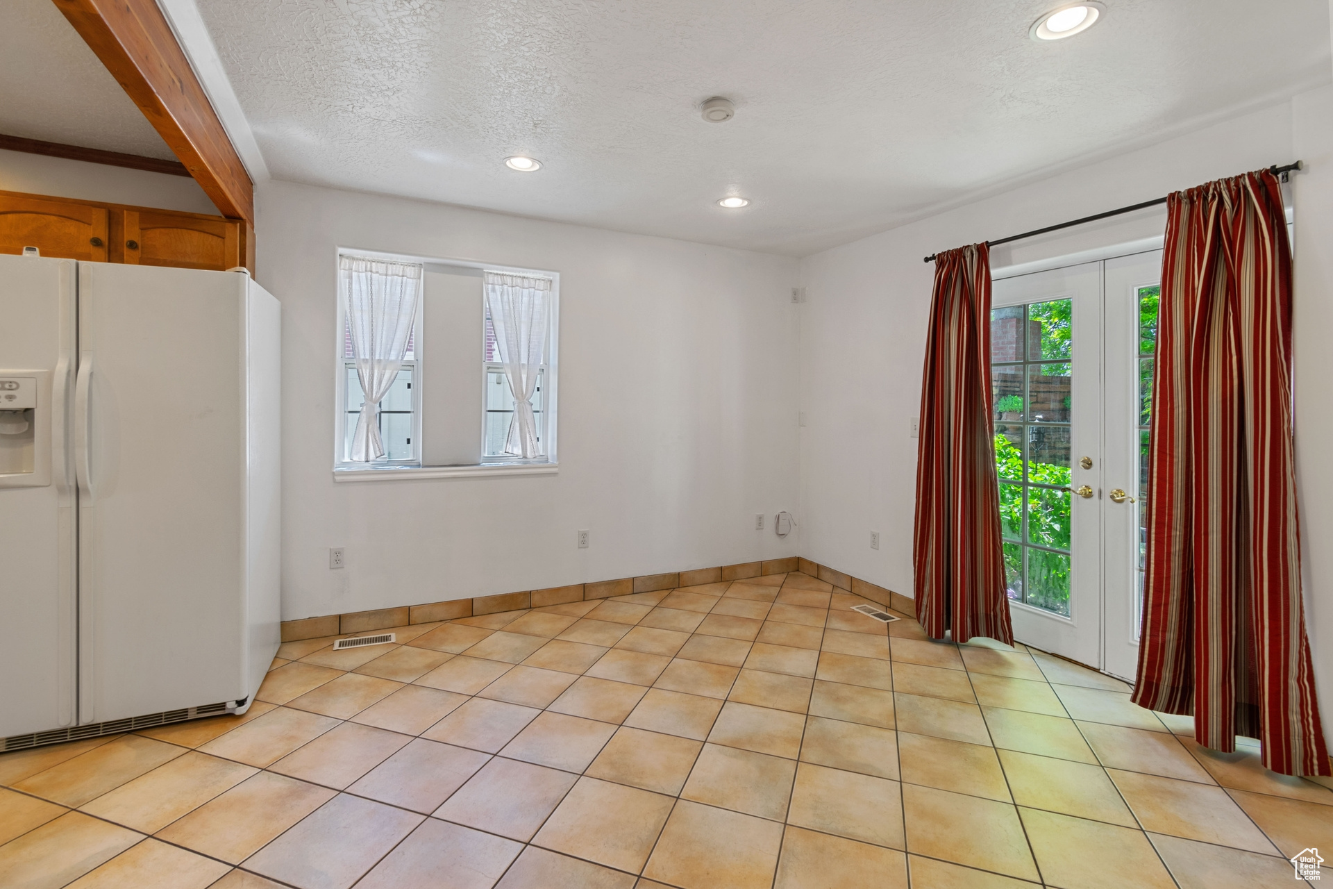 Interior space with a healthy amount of sunlight, a textured ceiling, french doors, and light tile floors