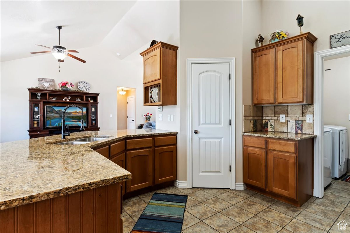 Kitchen featuring ceiling fan, light stone counters, light tile flooring, and sink