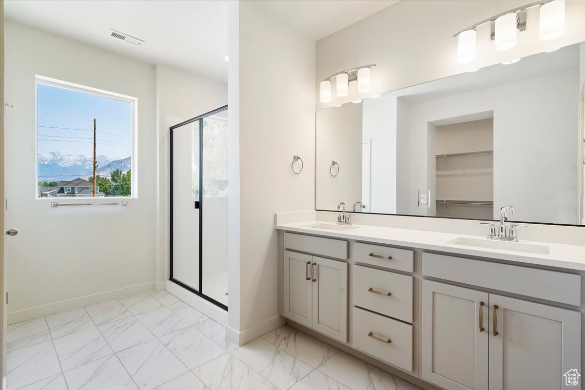 Bathroom featuring a shower with shower door, tile patterned floors, and dual bowl vanity