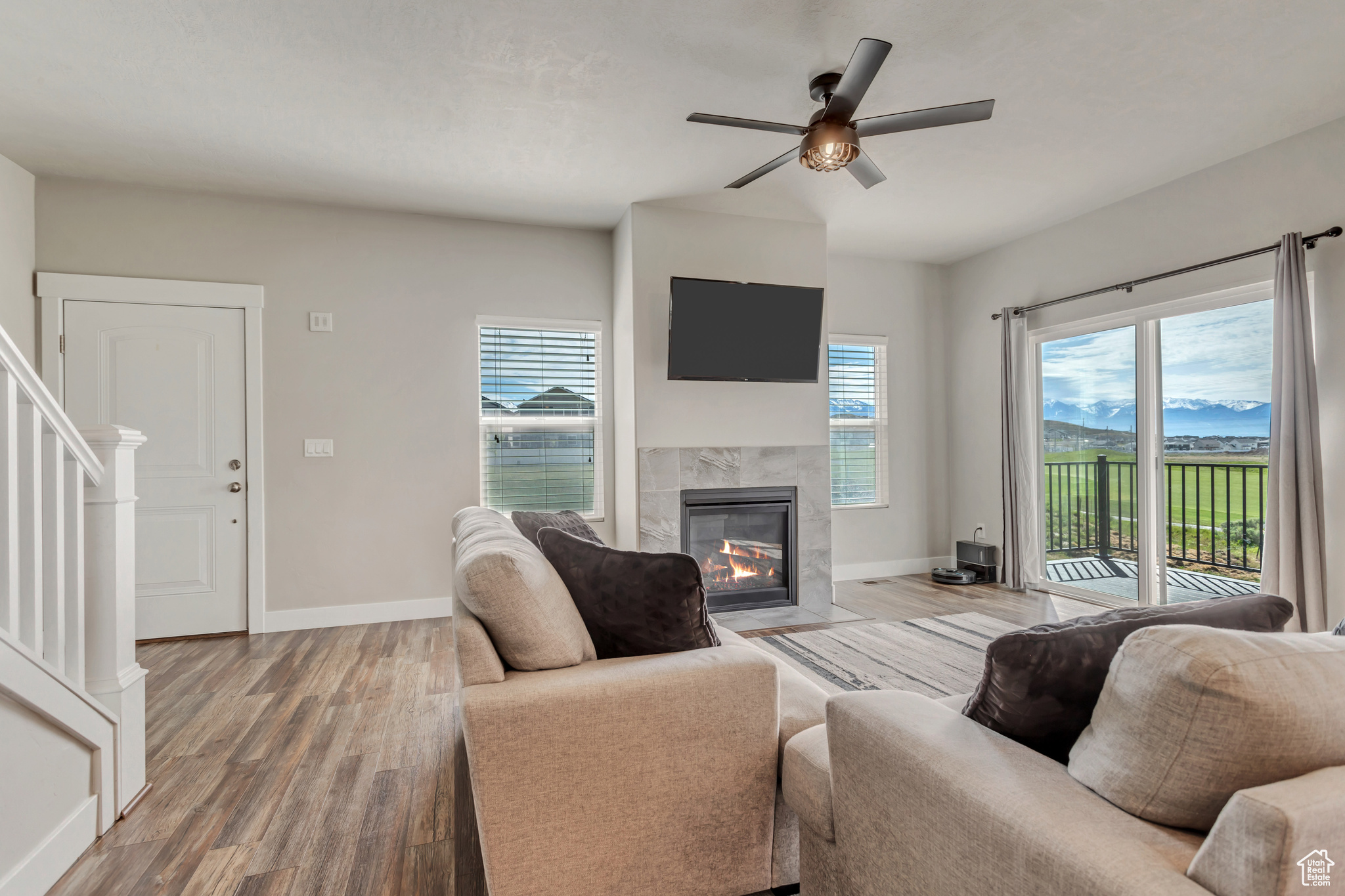 Living room with ceiling fan, hardwood / wood-style flooring, and a tile fireplace