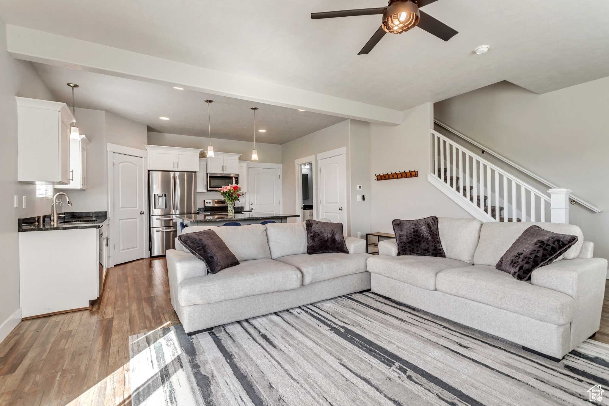 Living room featuring dark hardwood / wood-style floors, ceiling fan, sink, and beamed ceiling