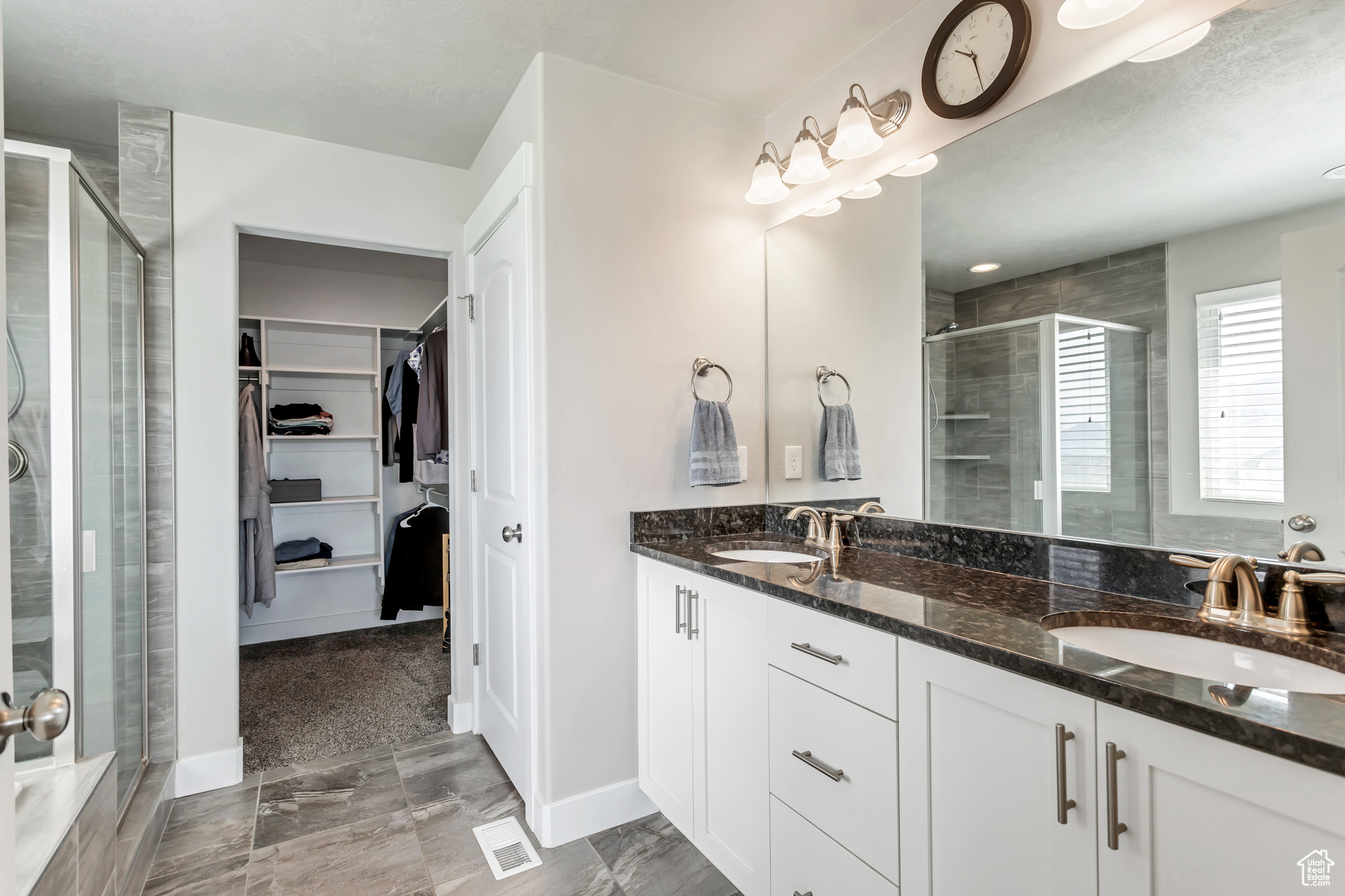 Bathroom with dual bowl vanity, an enclosed shower, and tile floors