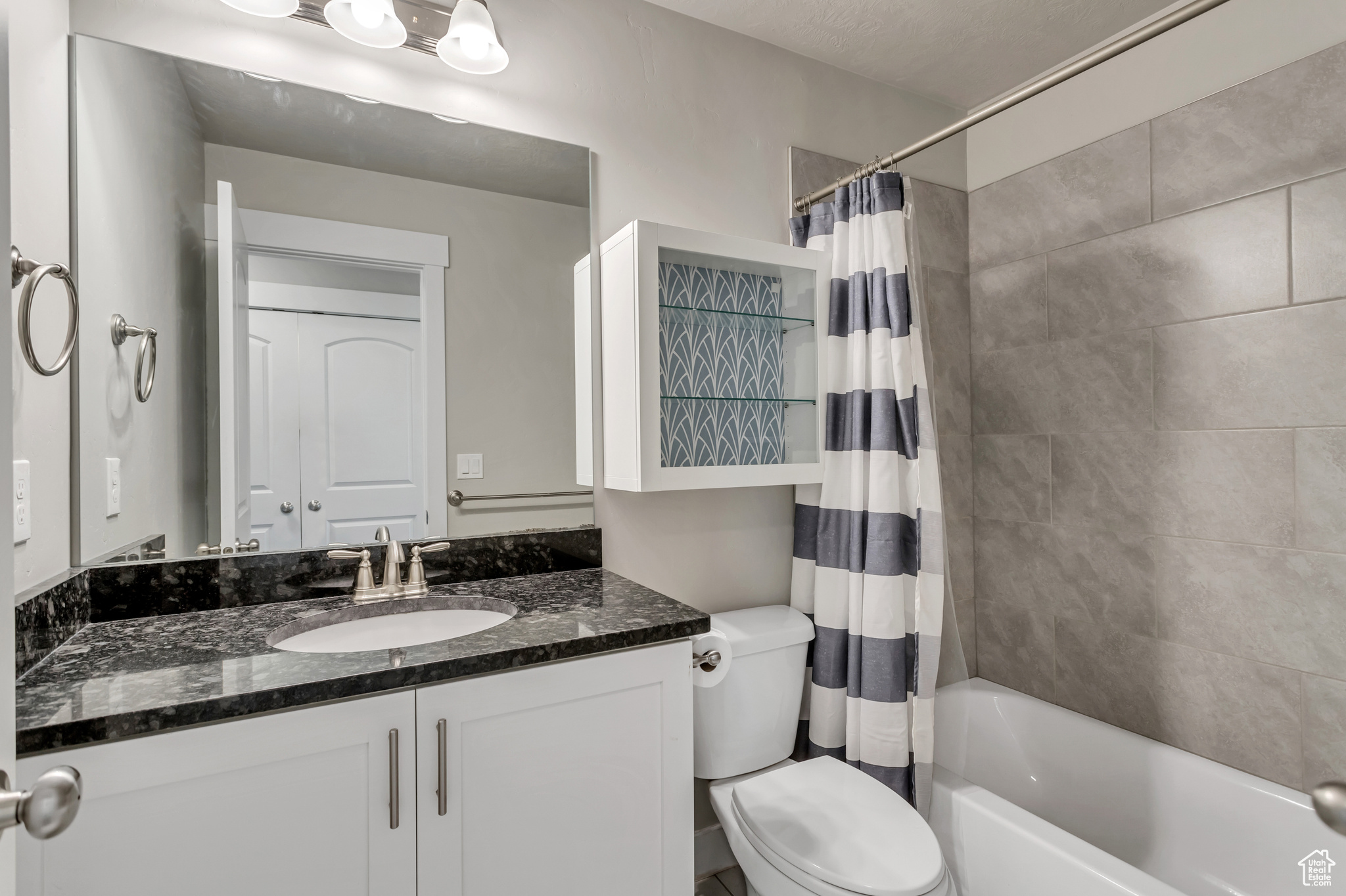 Full bathroom with vanity with extensive cabinet space, toilet, and shower / tub combo with curtain