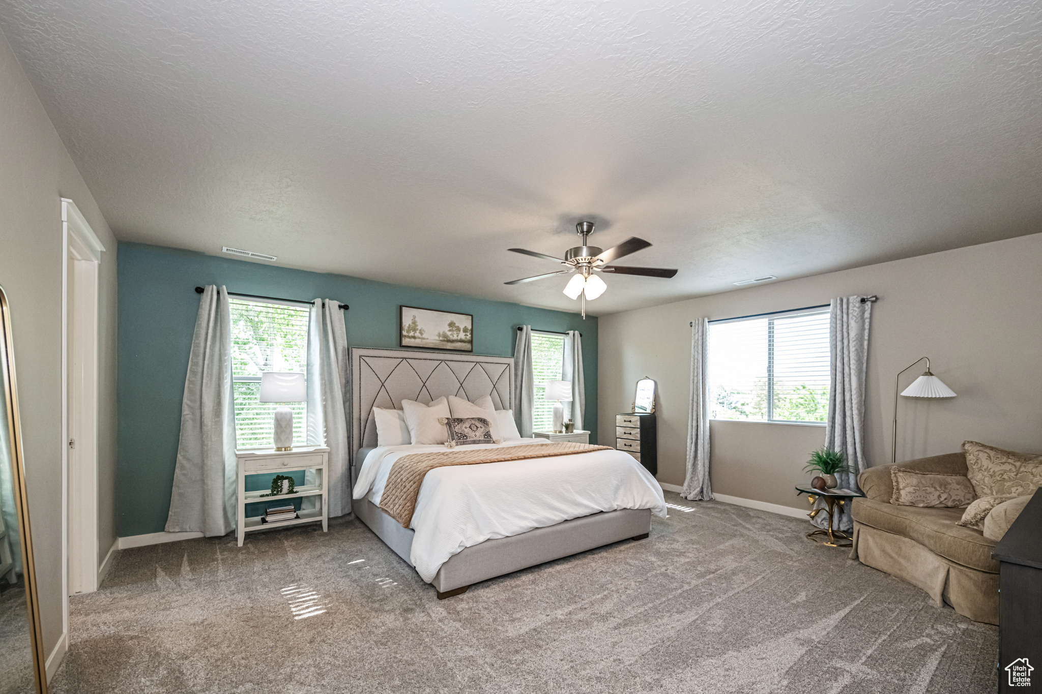 Oversized Primary Bedroom with lots of windows for natural daylight, carpet flooring, and ceiling fan.