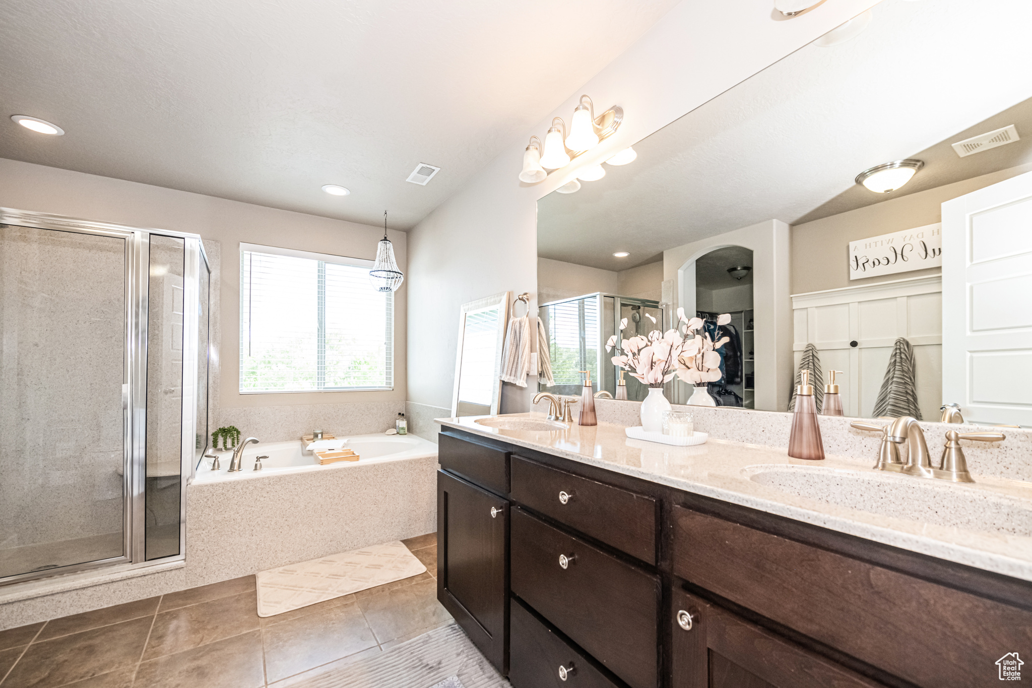 Primary onsuite with double sinks, tile flooring, shower with separate soaker bathtub, and large vanity.