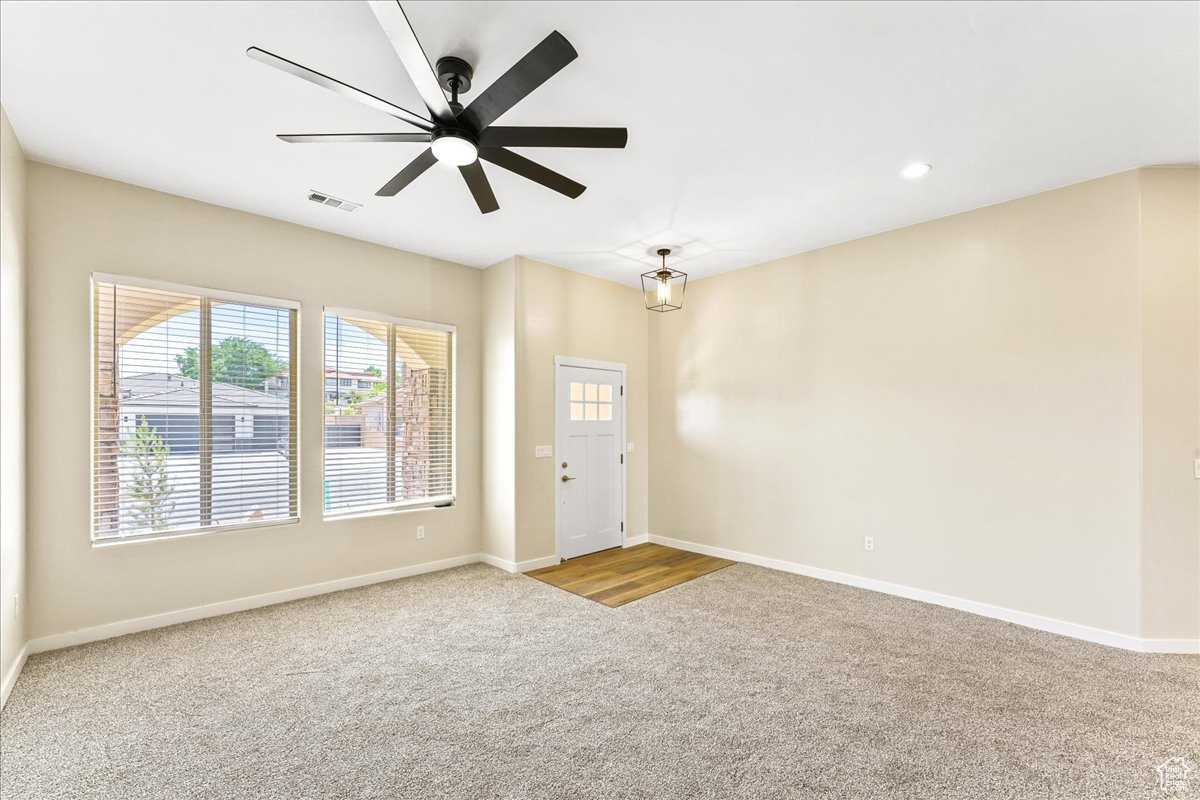 Carpeted foyer entrance with ceiling fan