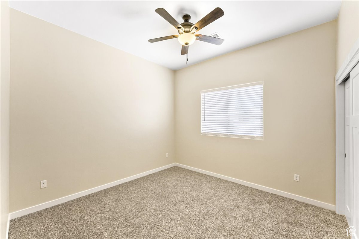 Empty room with carpet and ceiling fan