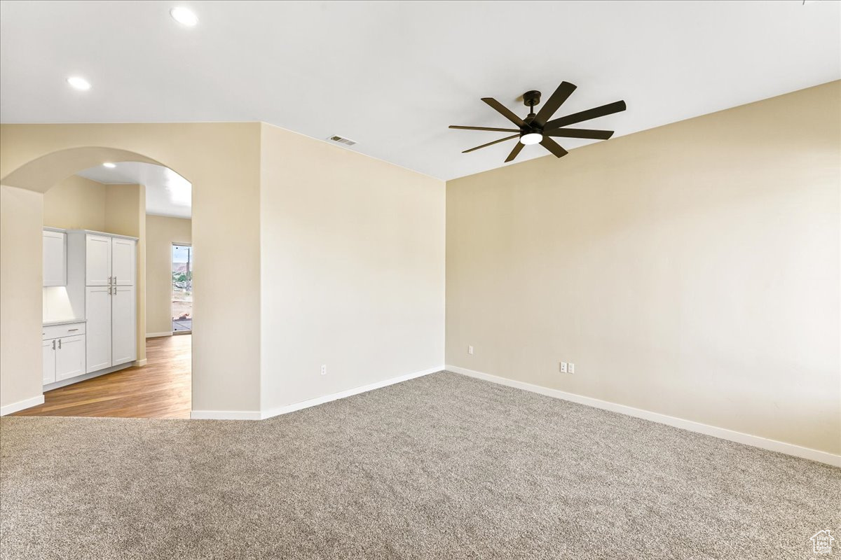 Empty room with light colored carpet and ceiling fan