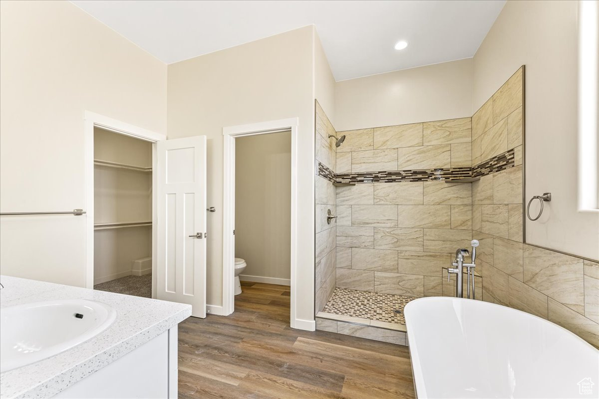 Full bathroom with independent shower and bath, wood-type flooring, vanity, and toilet