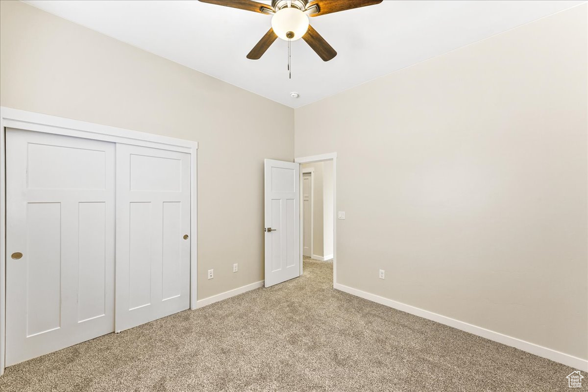 Unfurnished bedroom with light colored carpet, a closet, and ceiling fan