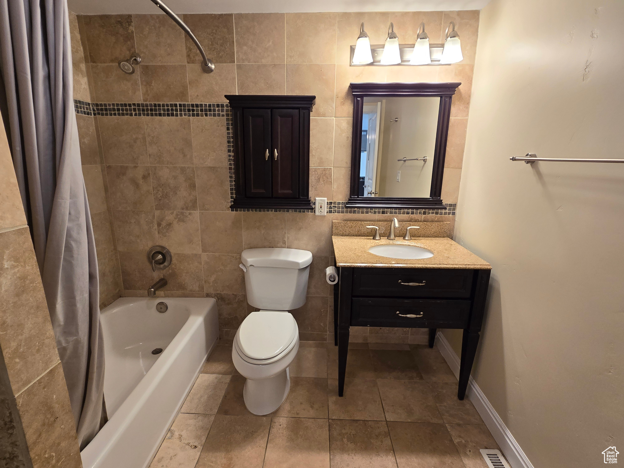 Full bathroom featuring shower / bath combo with shower curtain, tile flooring, tile walls, and vanity