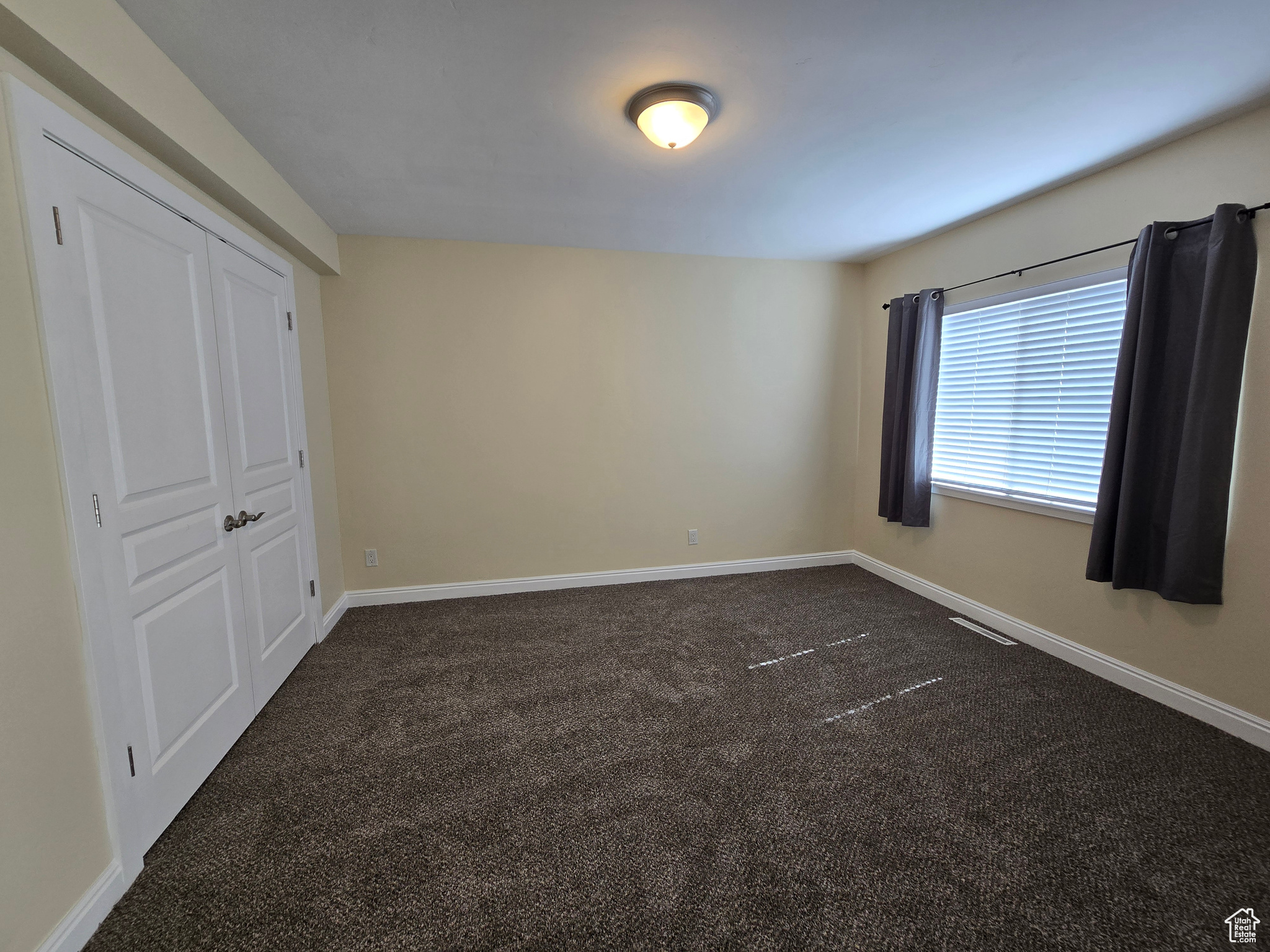 Unfurnished bedroom featuring dark carpet and a closet