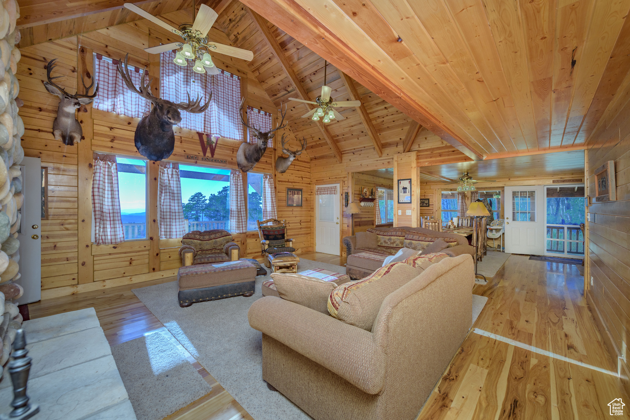 Living room with wooden ceiling, wooden walls, ceiling fan, and light hardwood / wood-style flooring