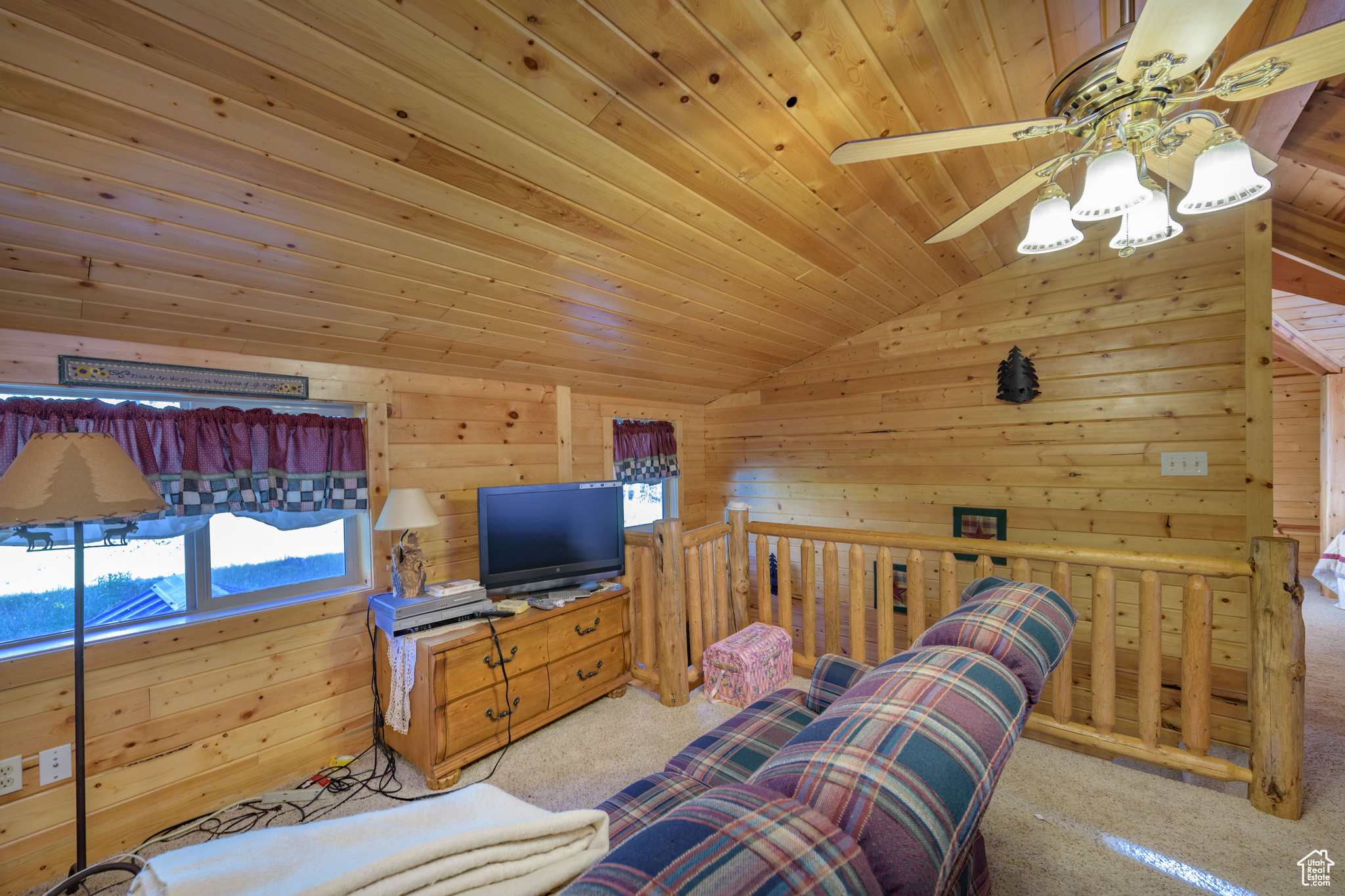 Interior space with wooden ceiling, wooden walls, ceiling fan, and vaulted ceiling