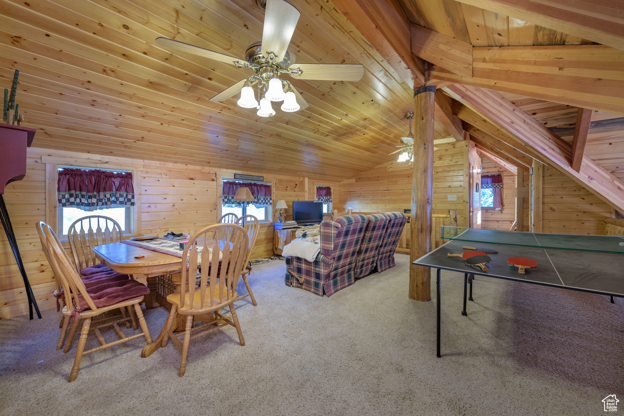 Dining area featuring wooden ceiling, wood walls, carpet, ceiling fan, and vaulted ceiling