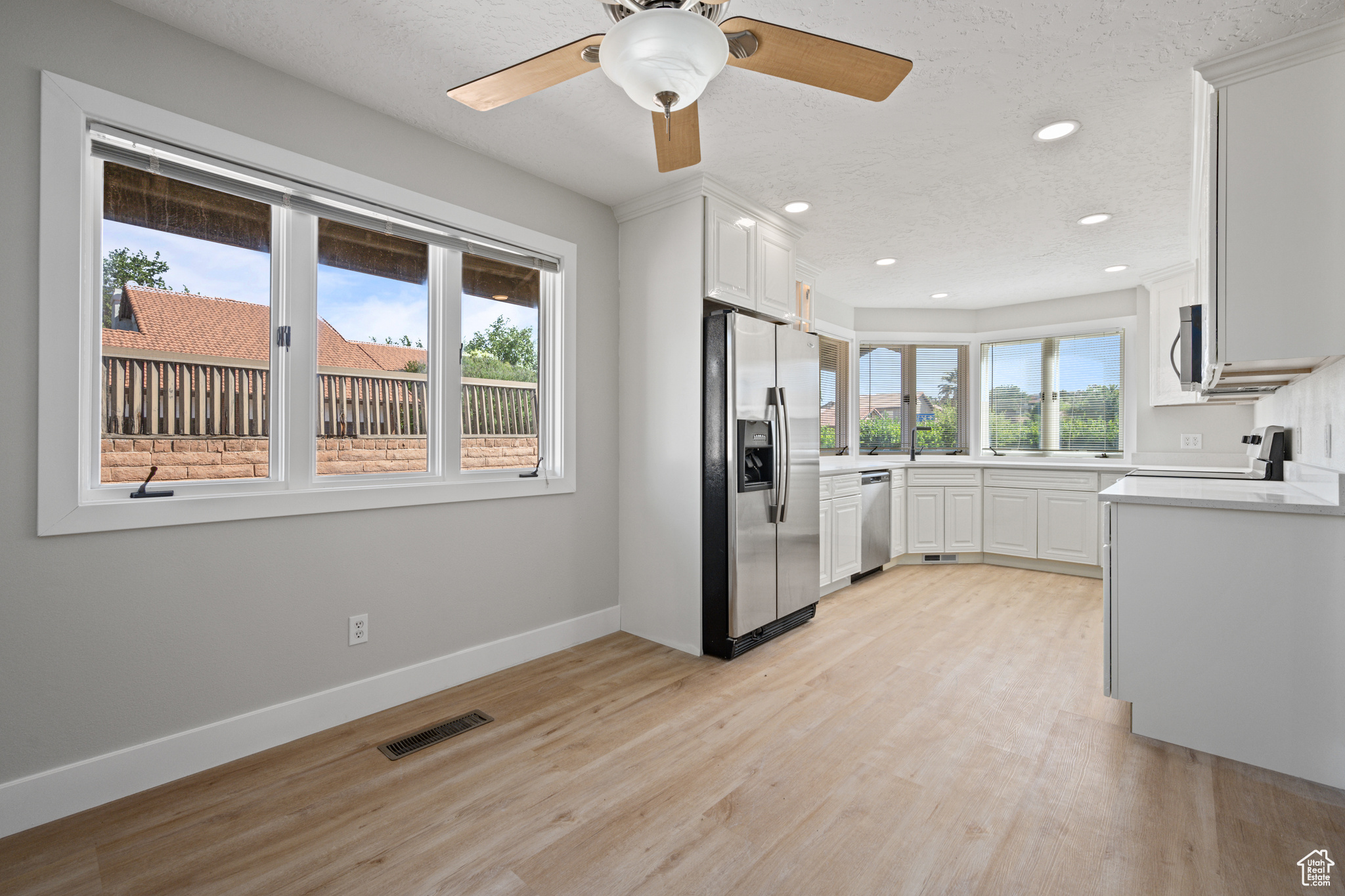 Kitchen featuring appliances with stainless steel finishes, white cabinets, ceiling fan, and light hardwood / wood-style flooring