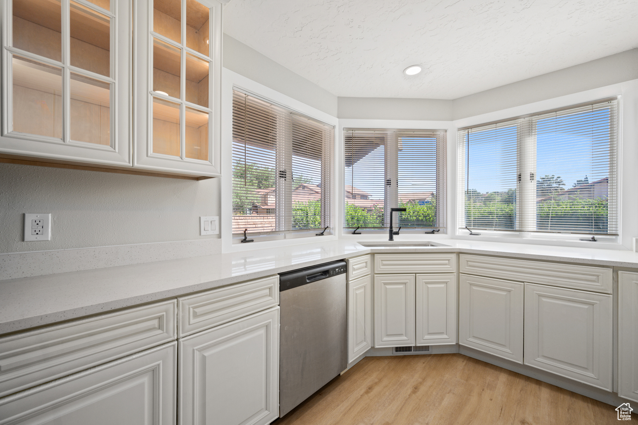 Kitchen featuring dishwasher, white cabinets, sink, and light hardwood / wood-style flooring