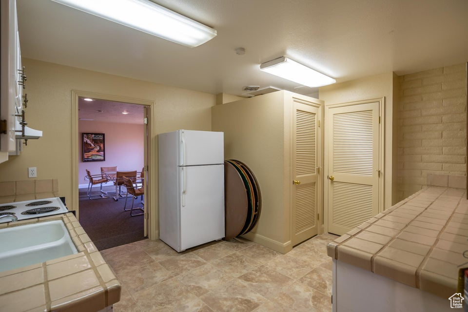 Kitchen featuring white appliances, tile counters, and sink