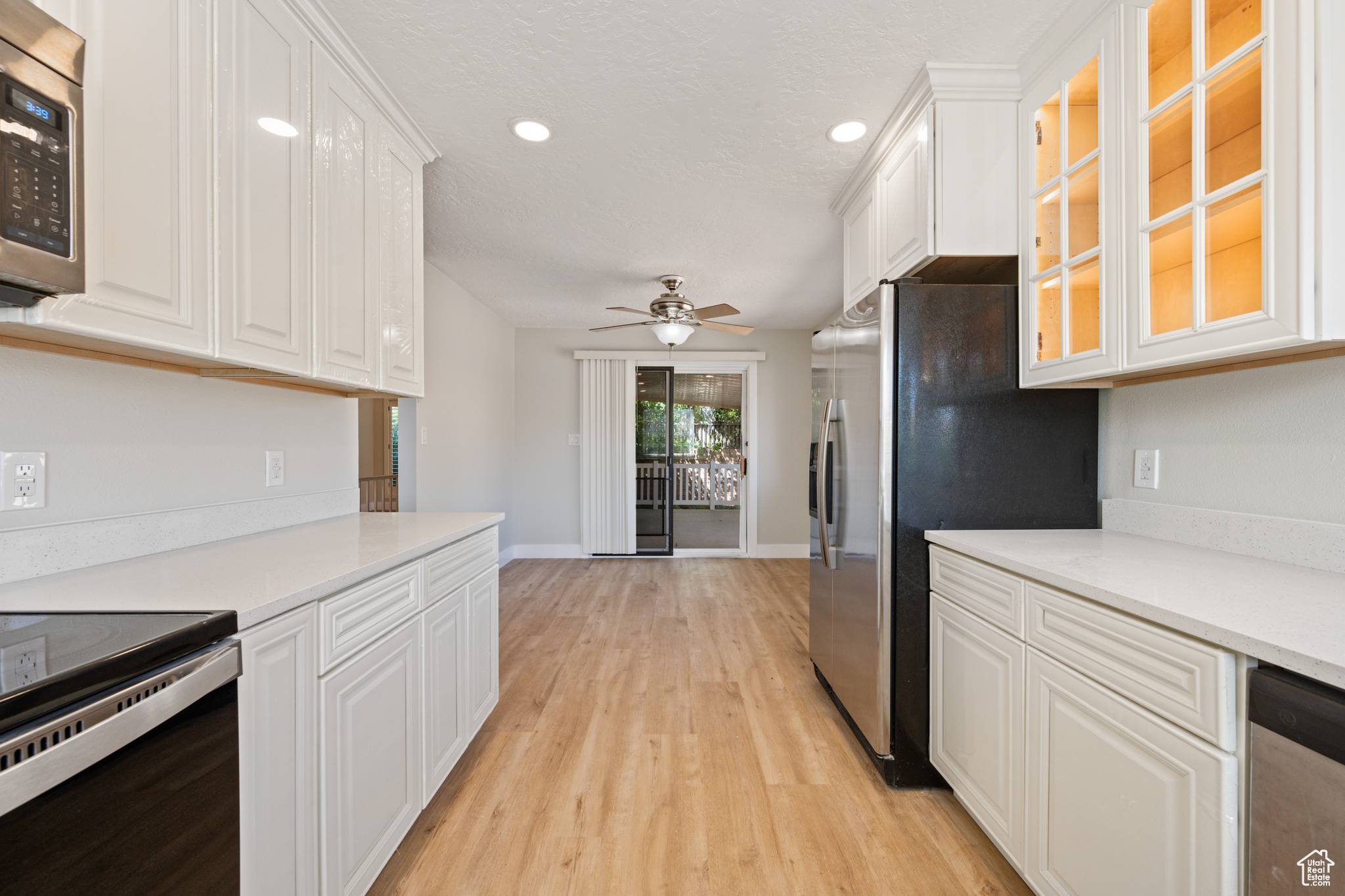 Kitchen featuring ceiling fan, stainless steel appliances, white cabinets, and light wood-type flooring